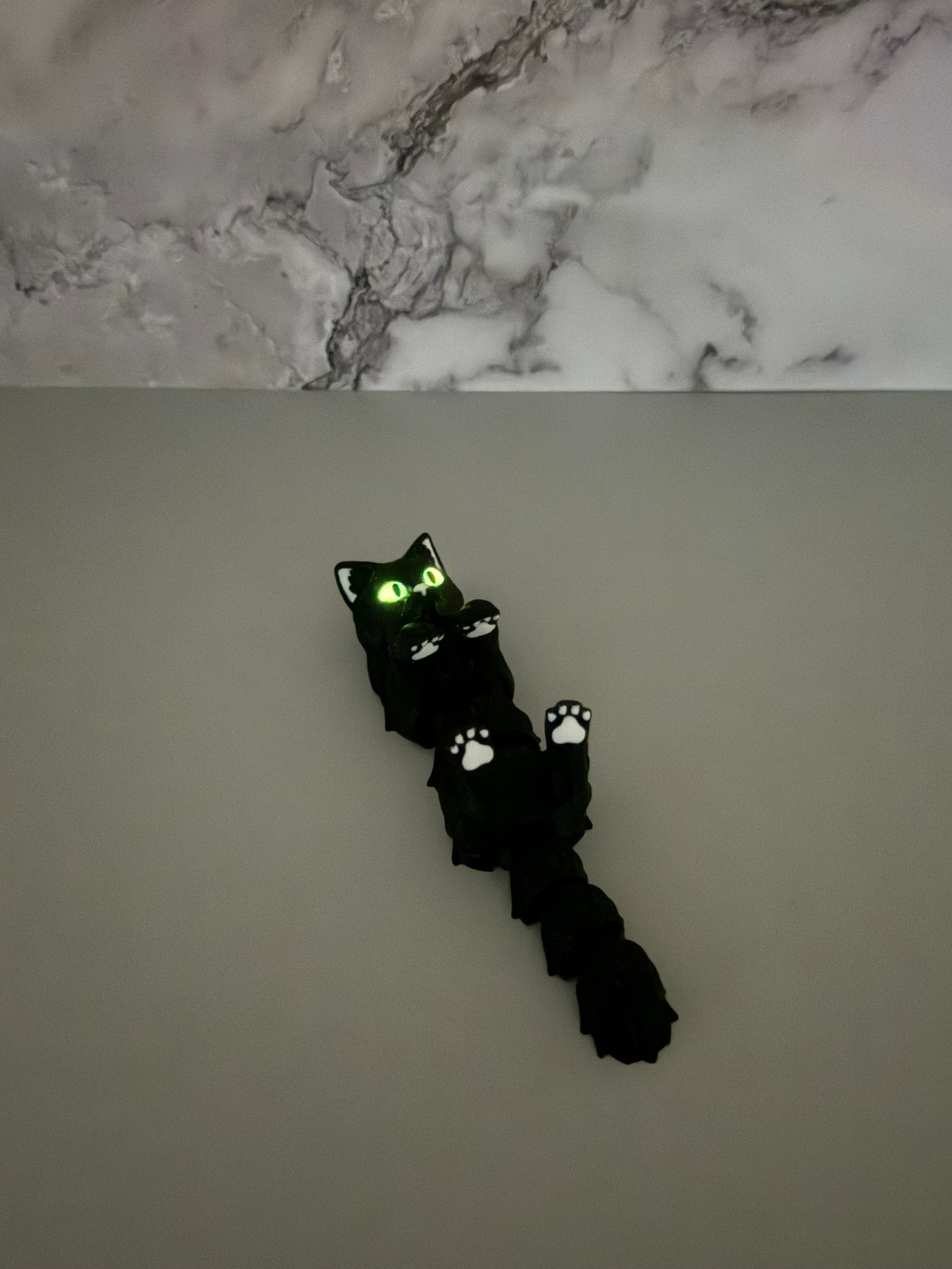 Toy black cat with glowing eyes on a plain background