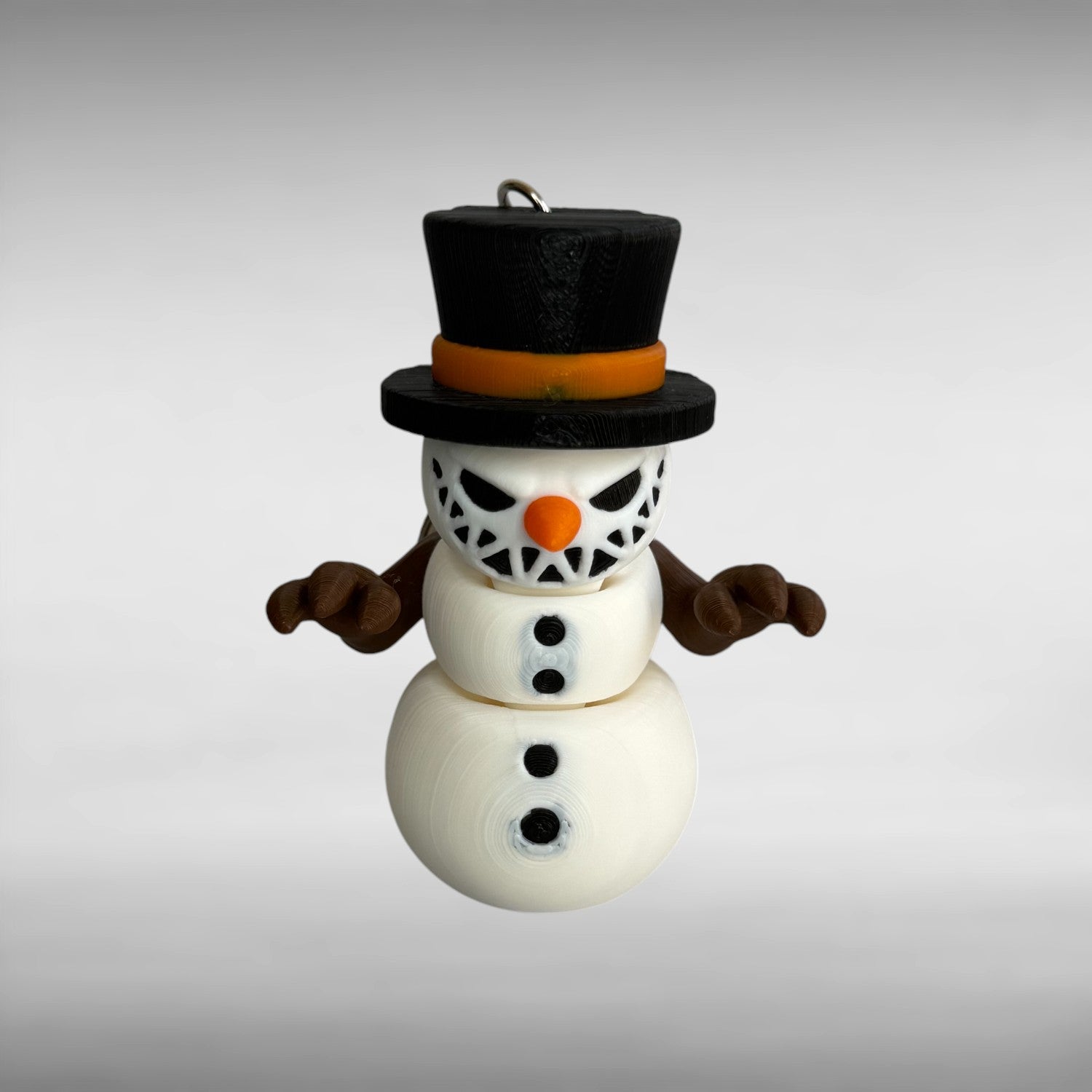Keychain of a small snowman with a sinister smile, black top hat, and an orange carrot nose on a gray background