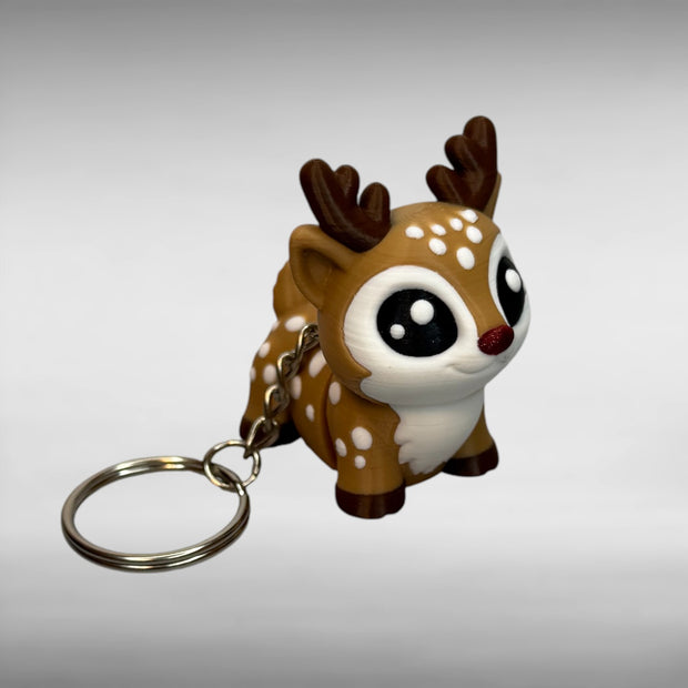 Reindeer-shaped keychain with a red, shimmer nose on a gray background