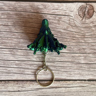 Top of a 3D printed keychain shaped like a dragon head with coral-like details, primarily in green and blue colors, placed on a wooden surface