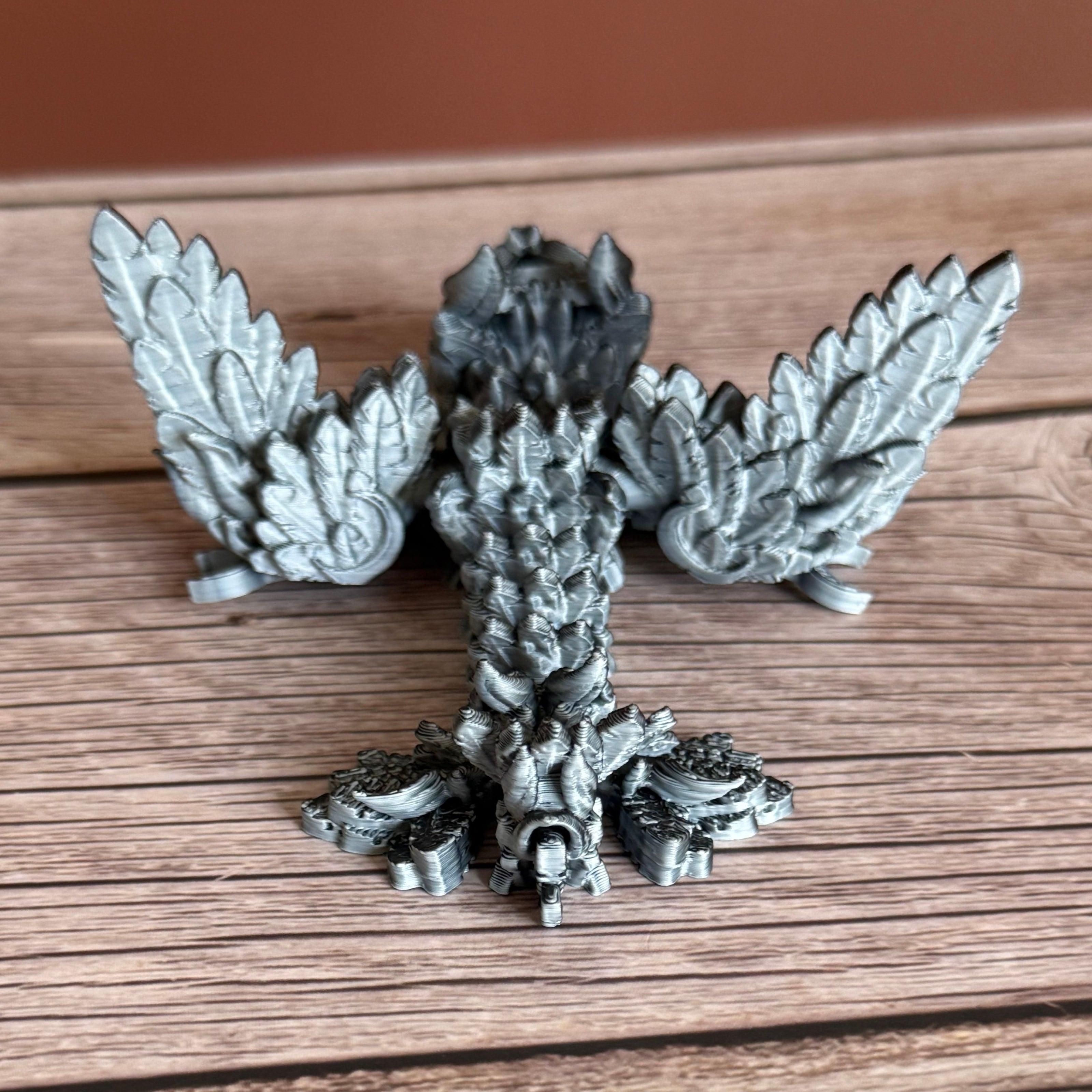 Back of a 3D printed, articulated dragon toy with black and white celestial-inspired patterns on a wooden surface.