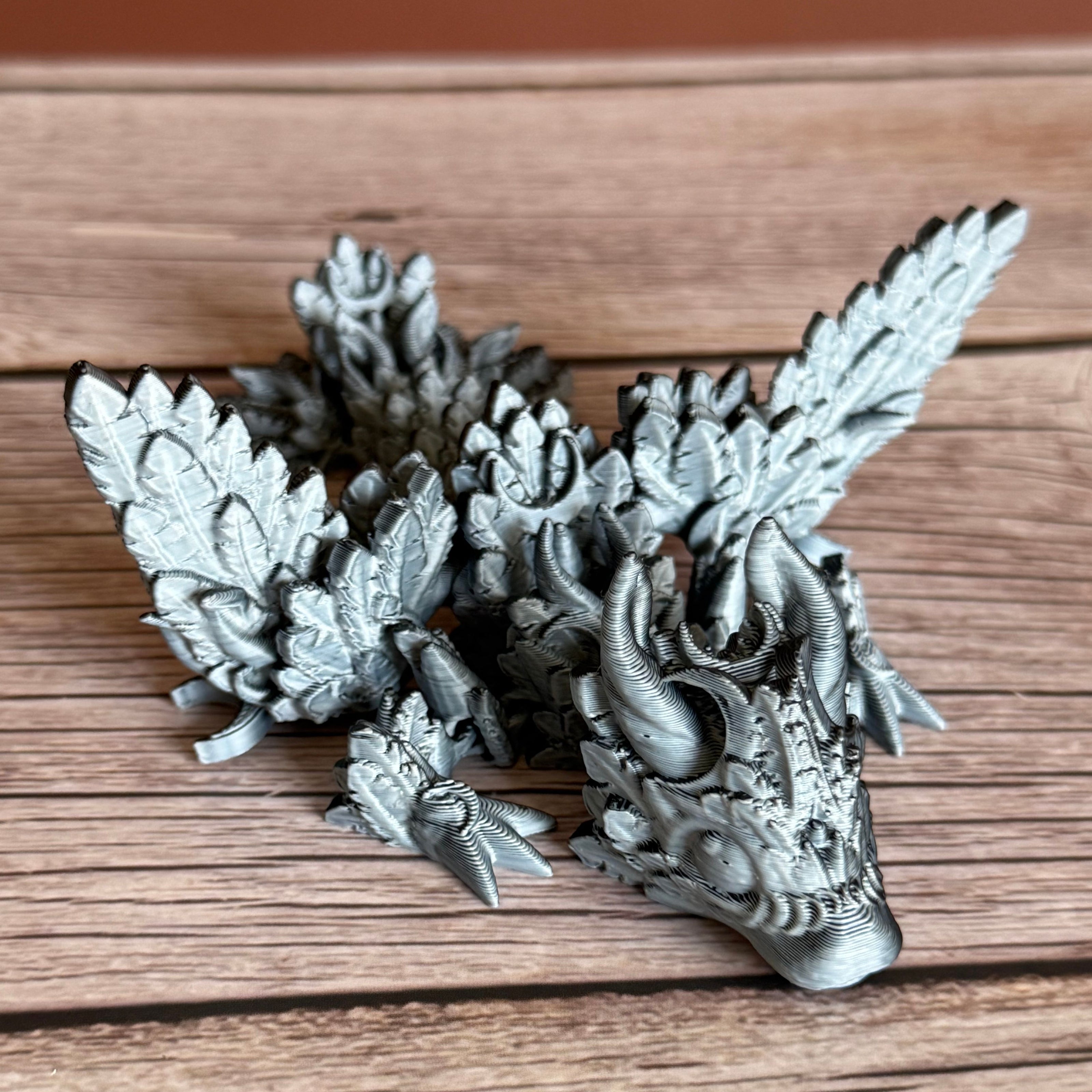 A 3D printed, articulated dragon toy with black and white celestial-inspired patterns on a wooden surface.