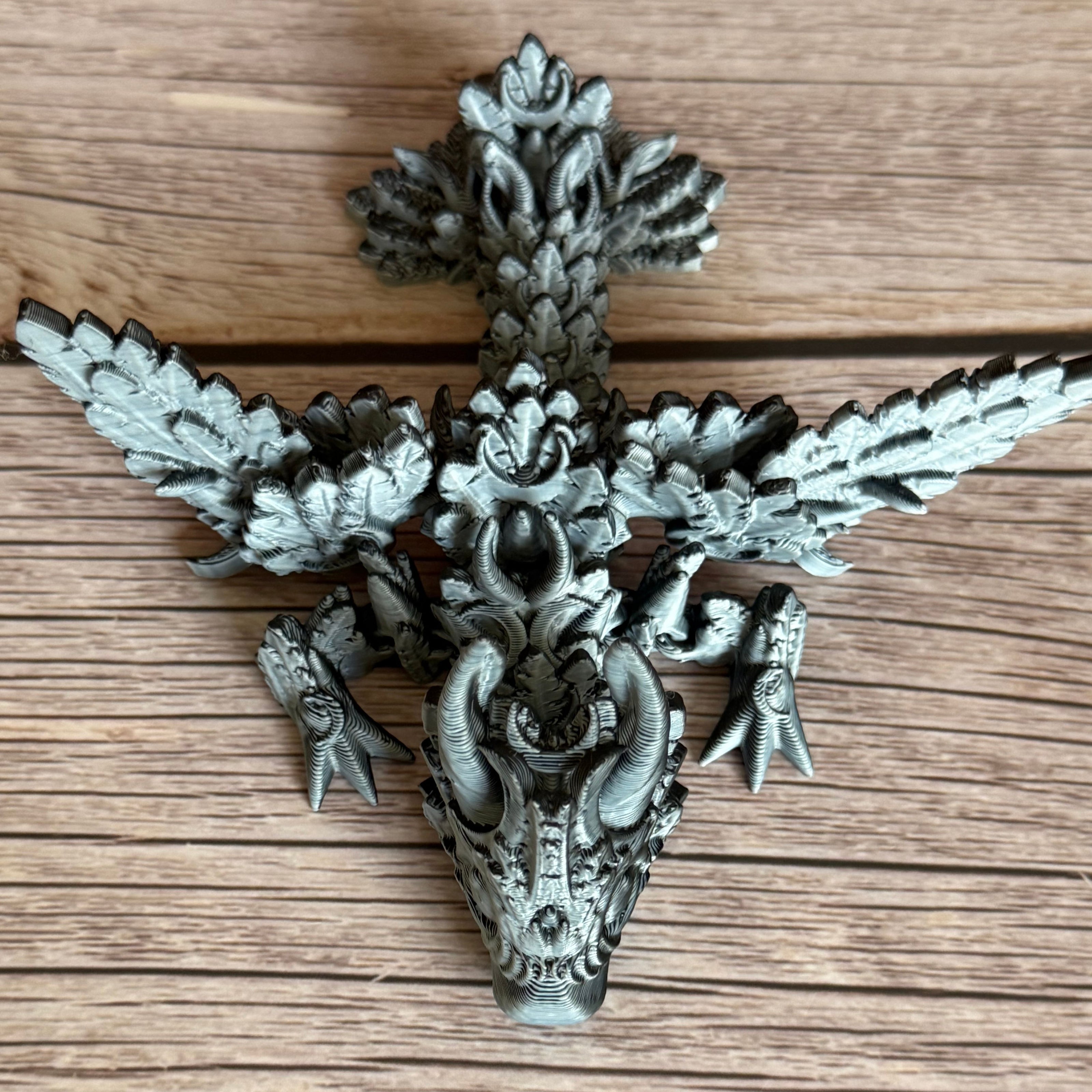 A 3D printed, articulated dragon toy with black and white celestial-inspired patterns on a wooden surface.
