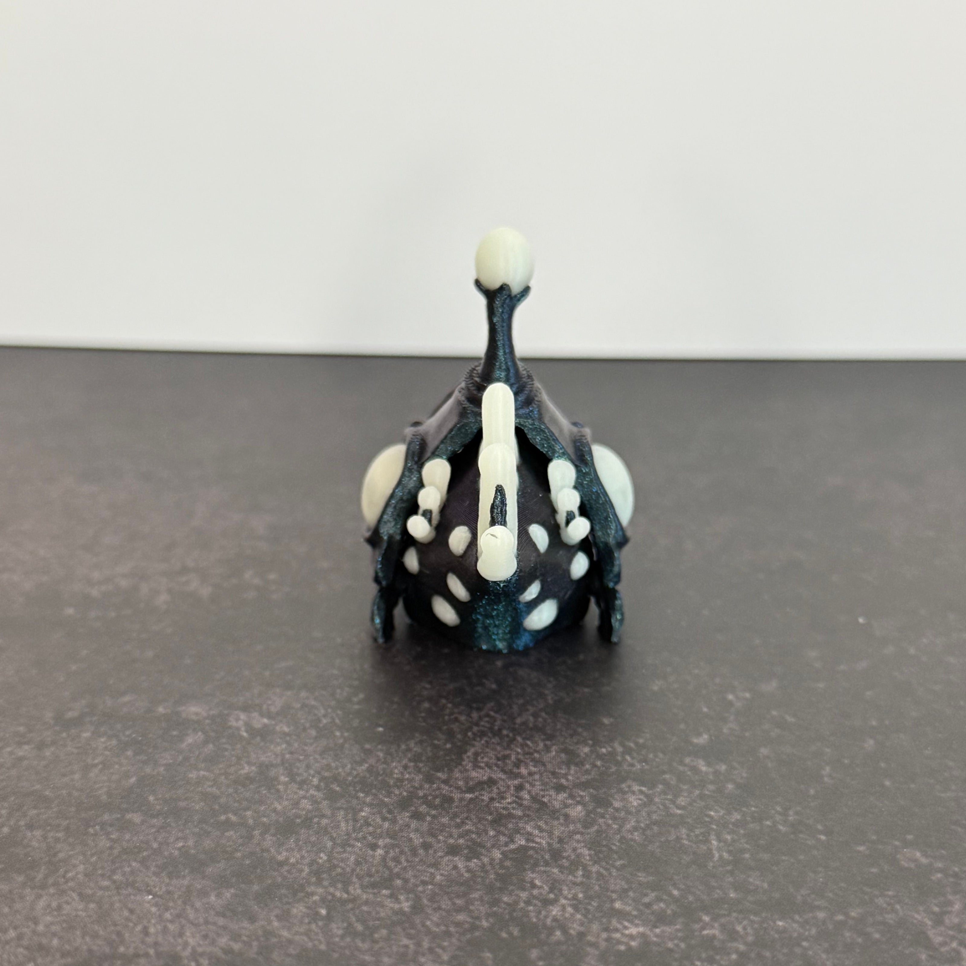 Sparkly blue angler fish figurine with white accents on a black and gray background