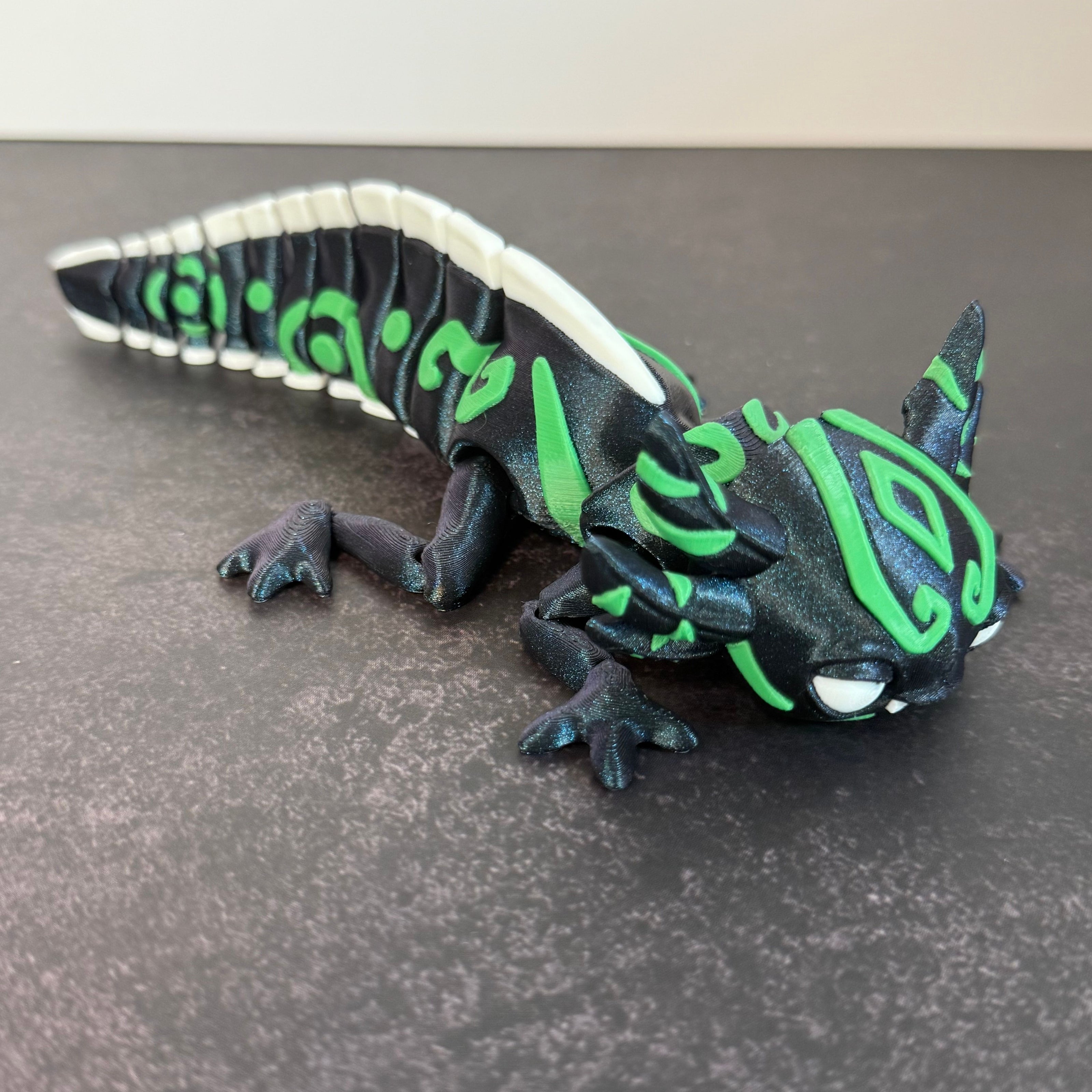 toy axolotl figure with blue, green, and white markings on a black and gray background