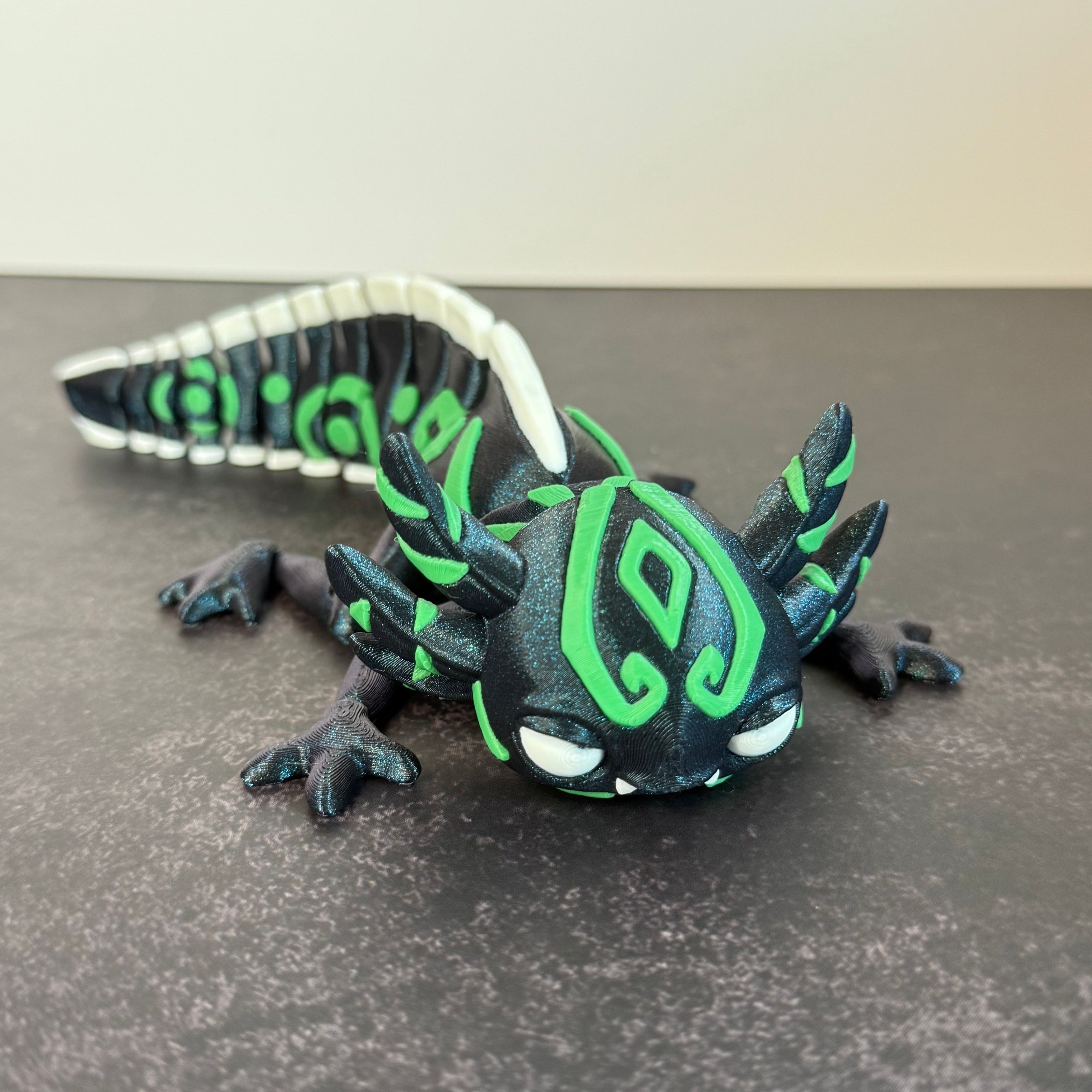 toy axolotl figure with blue, green, and white markings on a black and gray background