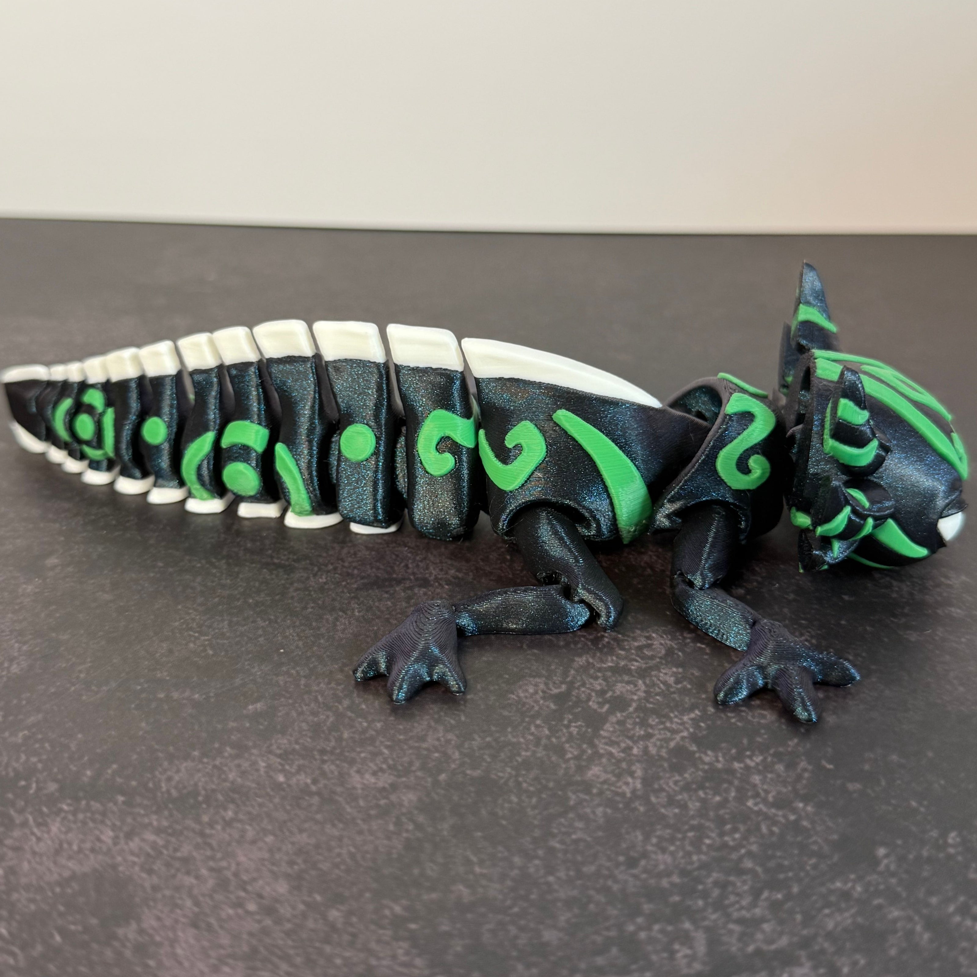 toy axolotl figure with blue, green, and white markings on a black and gray background