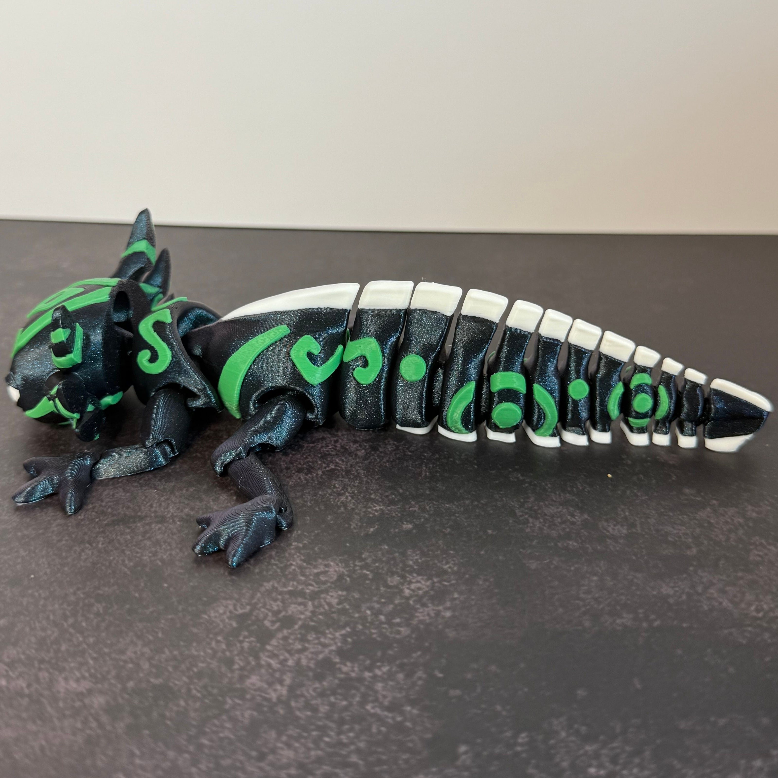 toy axolotl figure with blue, green, and white markings on a black and gray background