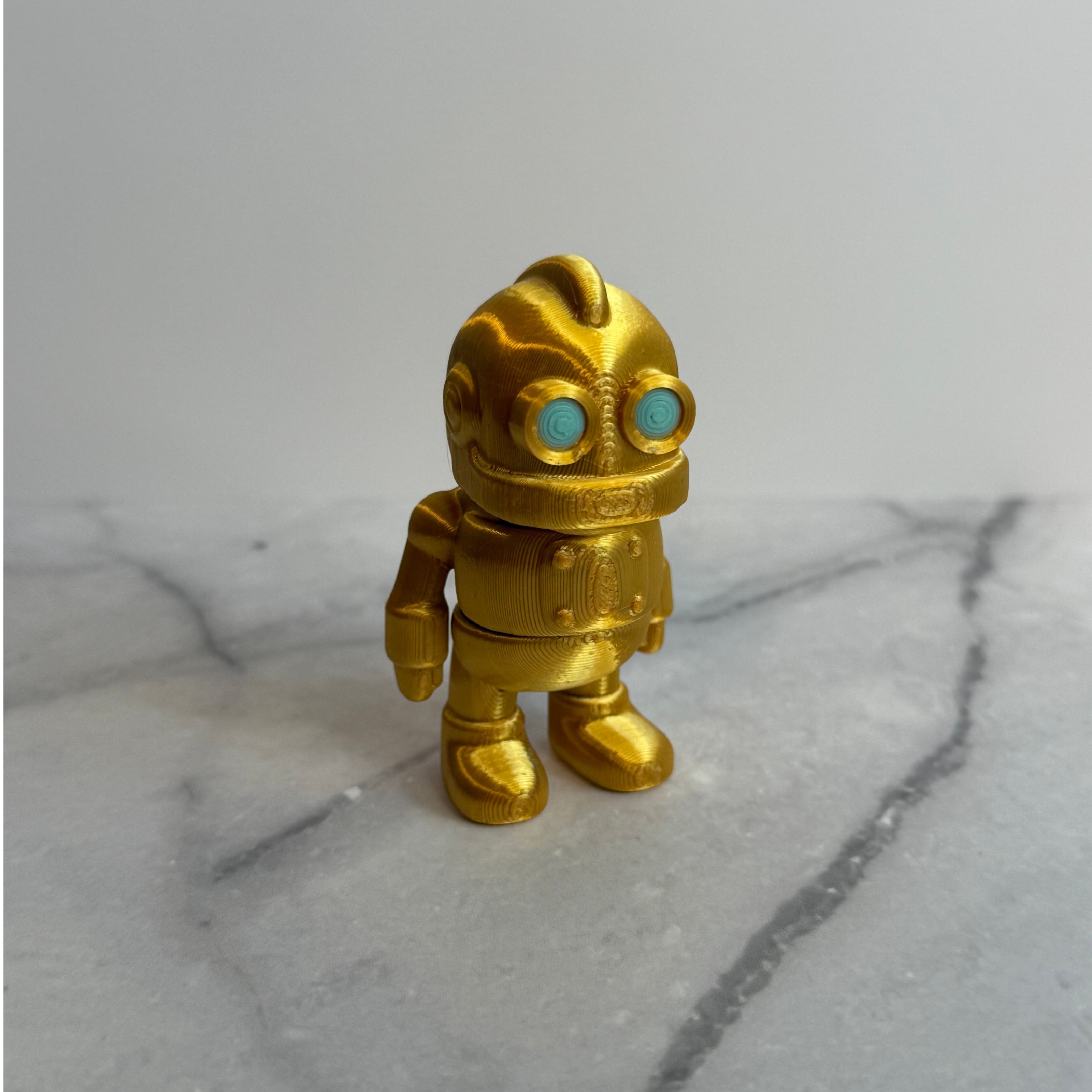 Gold robot figurine with turquoise eyes on a marble surface