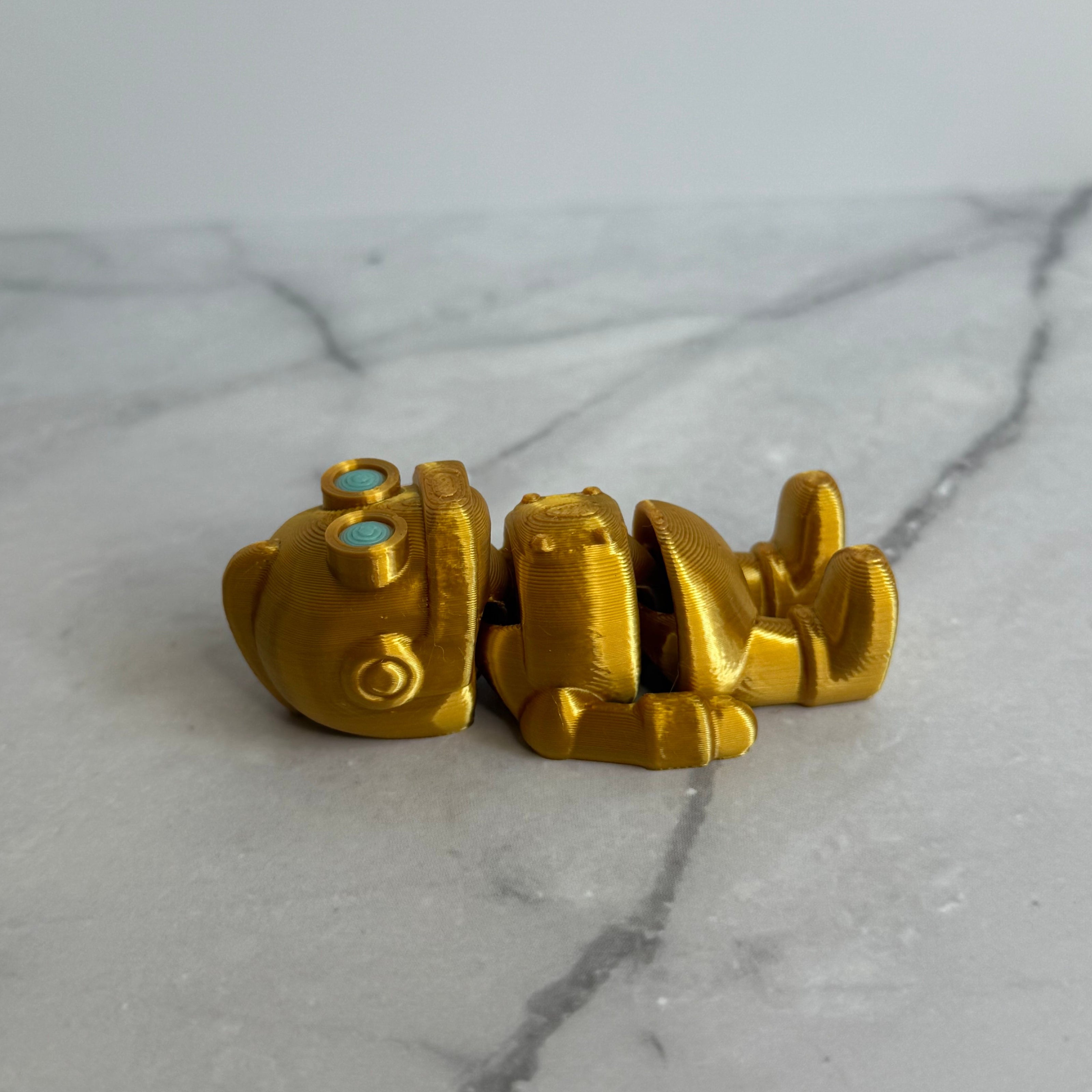 Gold robot figurine with turquoise eyes on a marble background