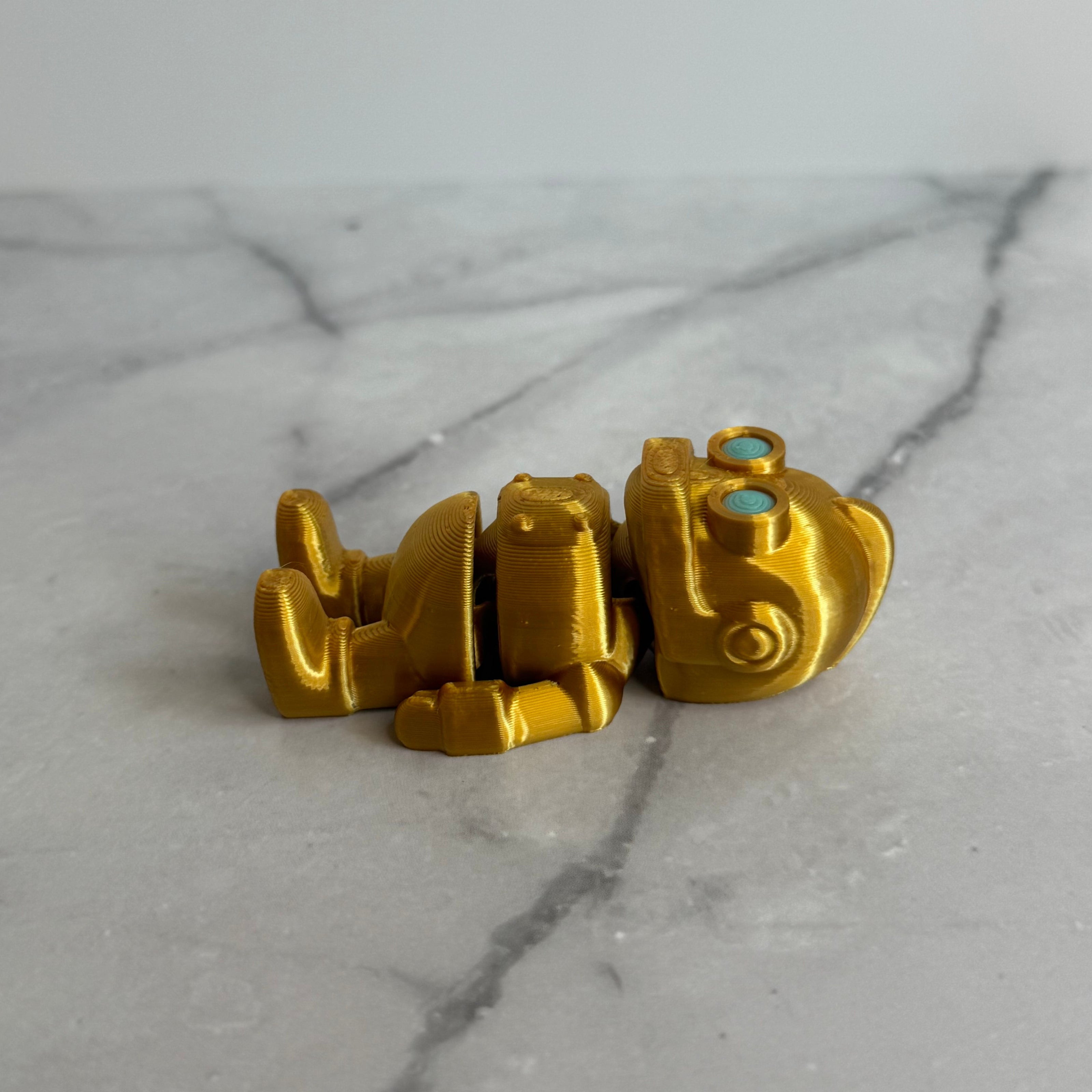 Gold robot figurine with turquoise eyes on a marble background
