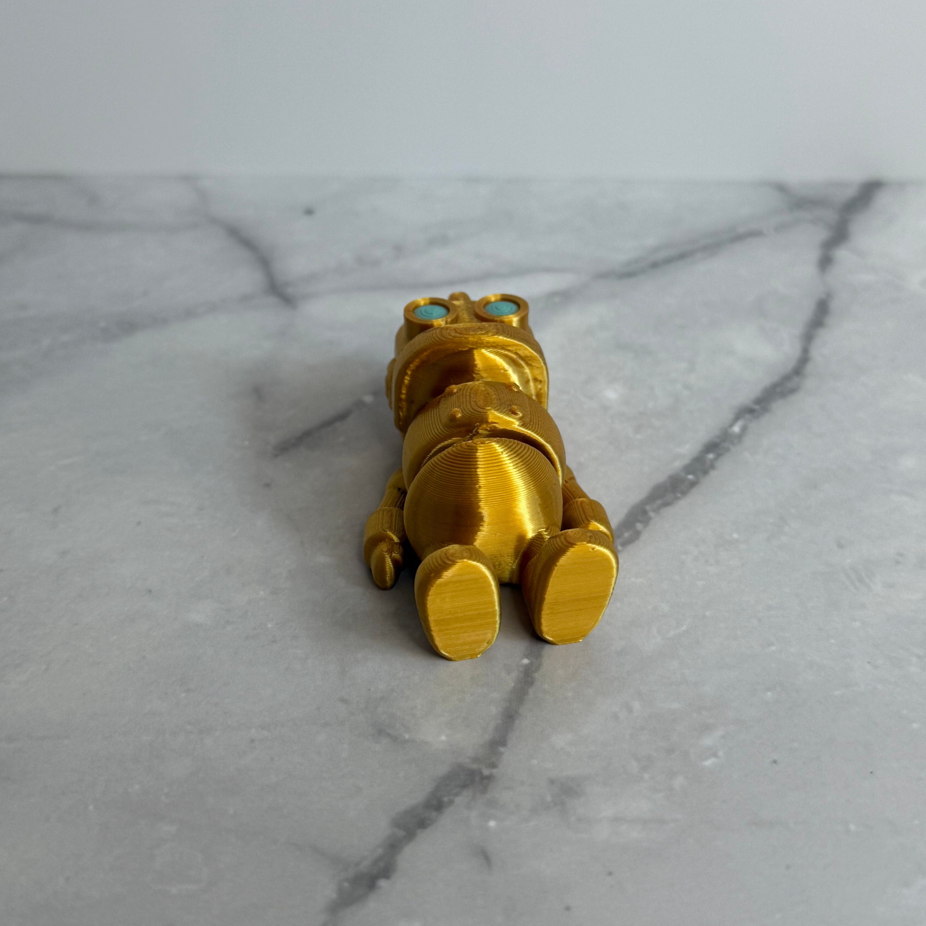 Gold robot figurine with turquoise eyes on a marble background