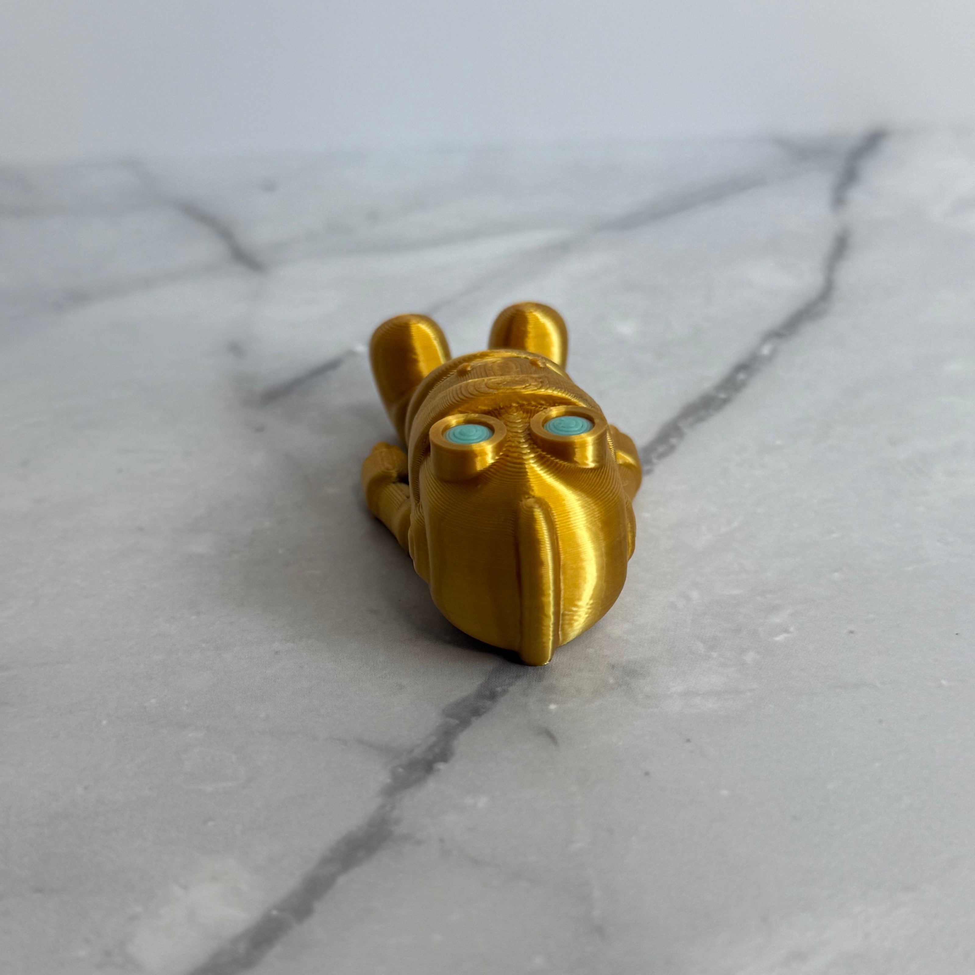 Gold robot figurine with turquoise eyes on a marble background