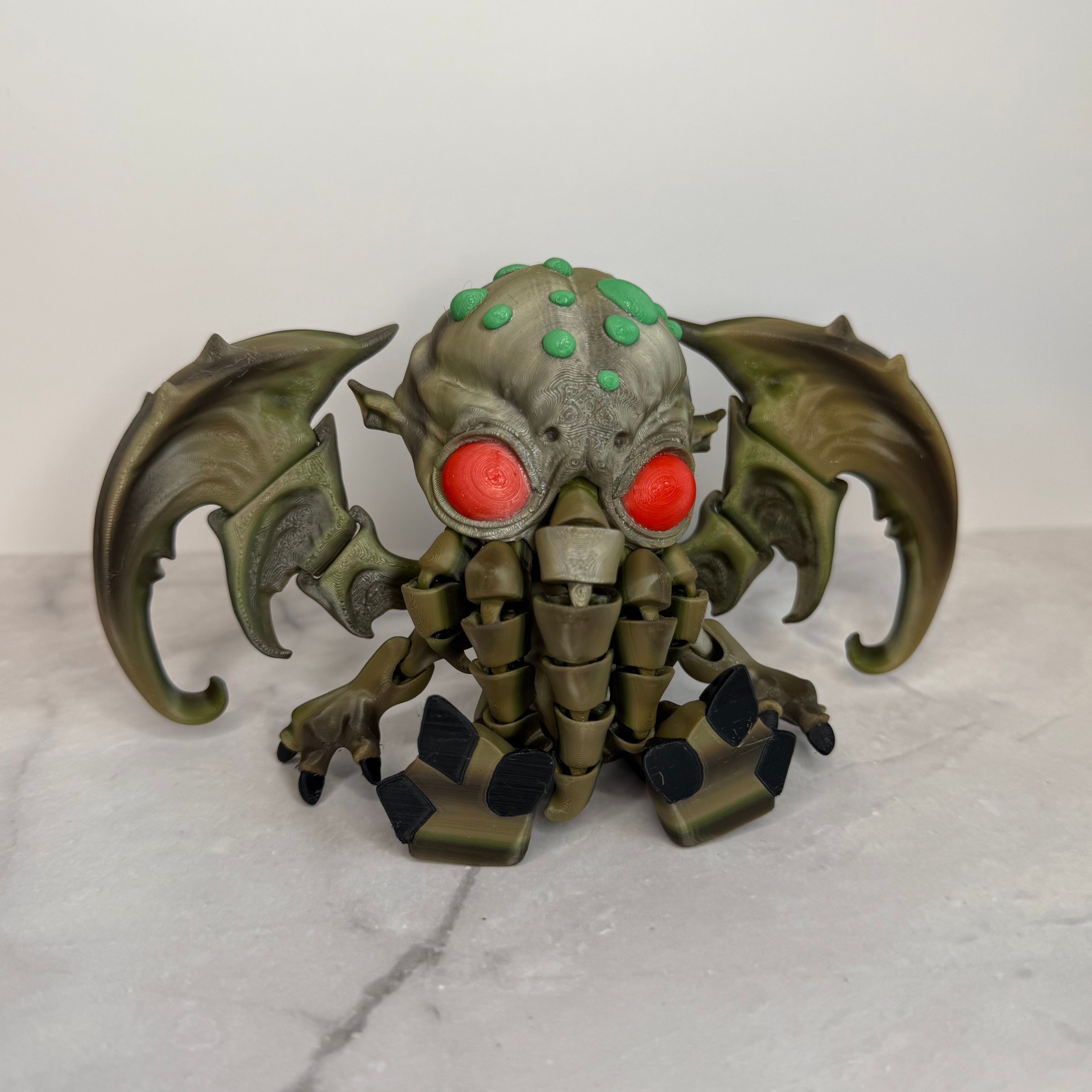 Toy figure of a creature with red eyes and green accents on a marble surface