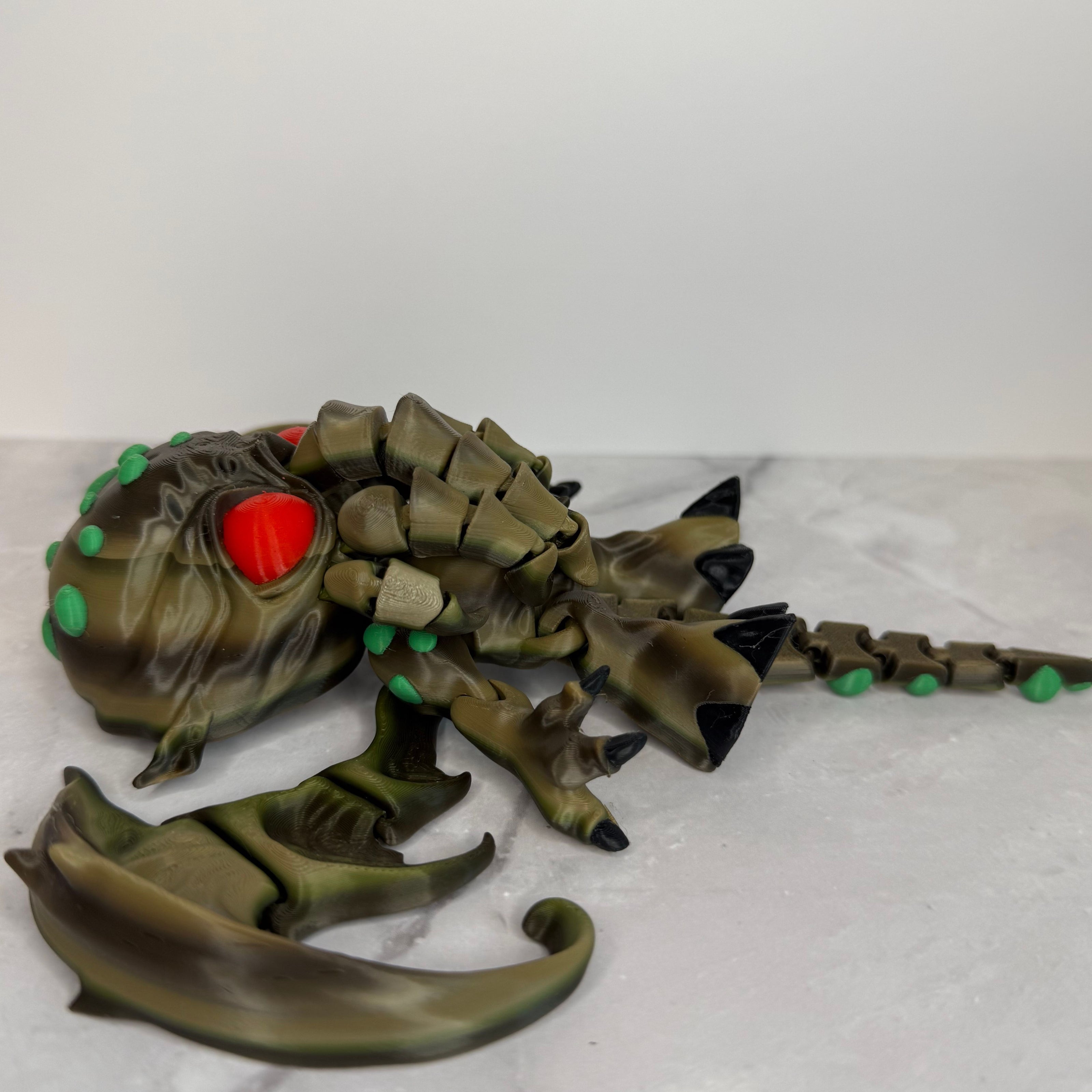 Toy figure of a creature with red eyes and green accents on a gray background