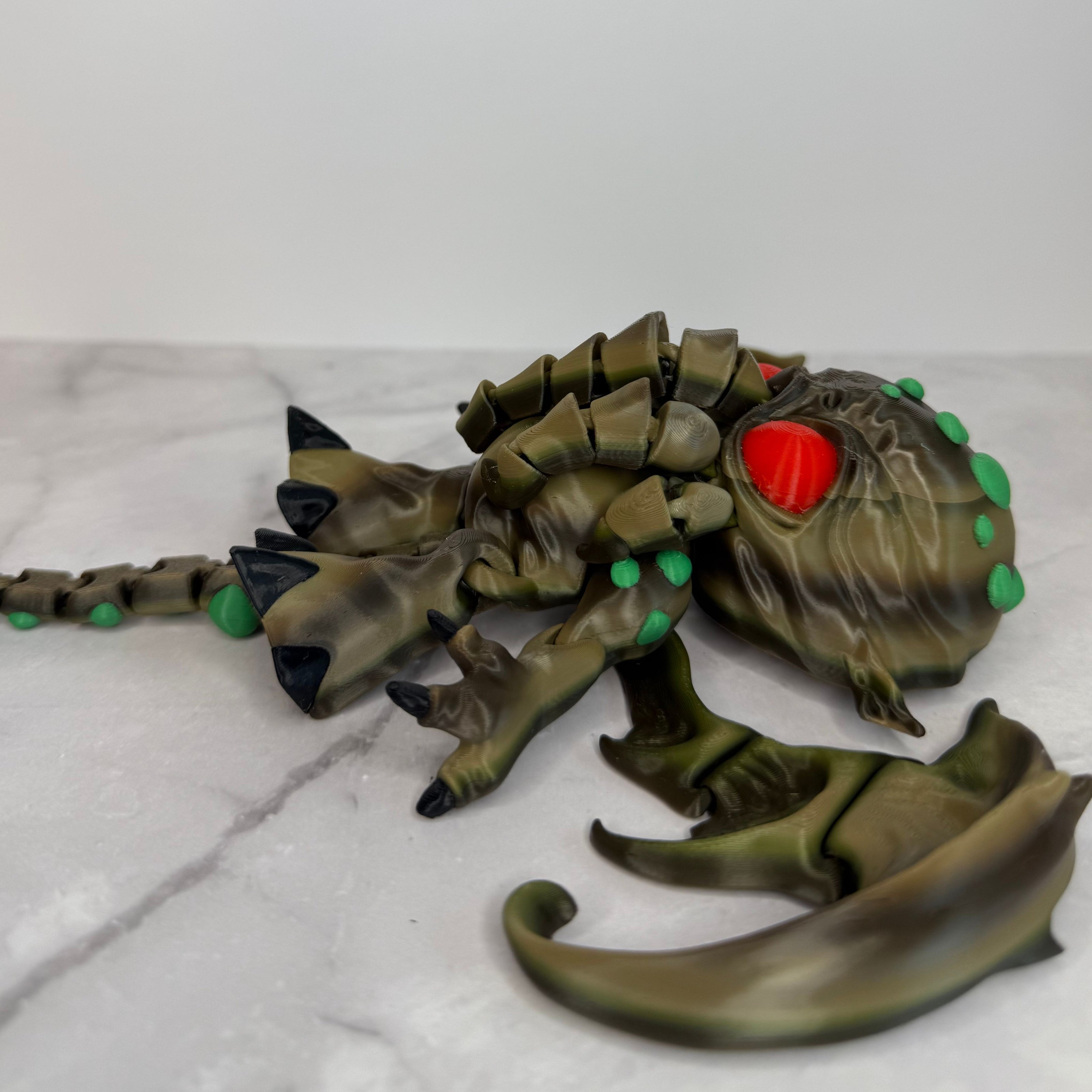 Toy figure of a creature with red eyes and green accents on a gray background