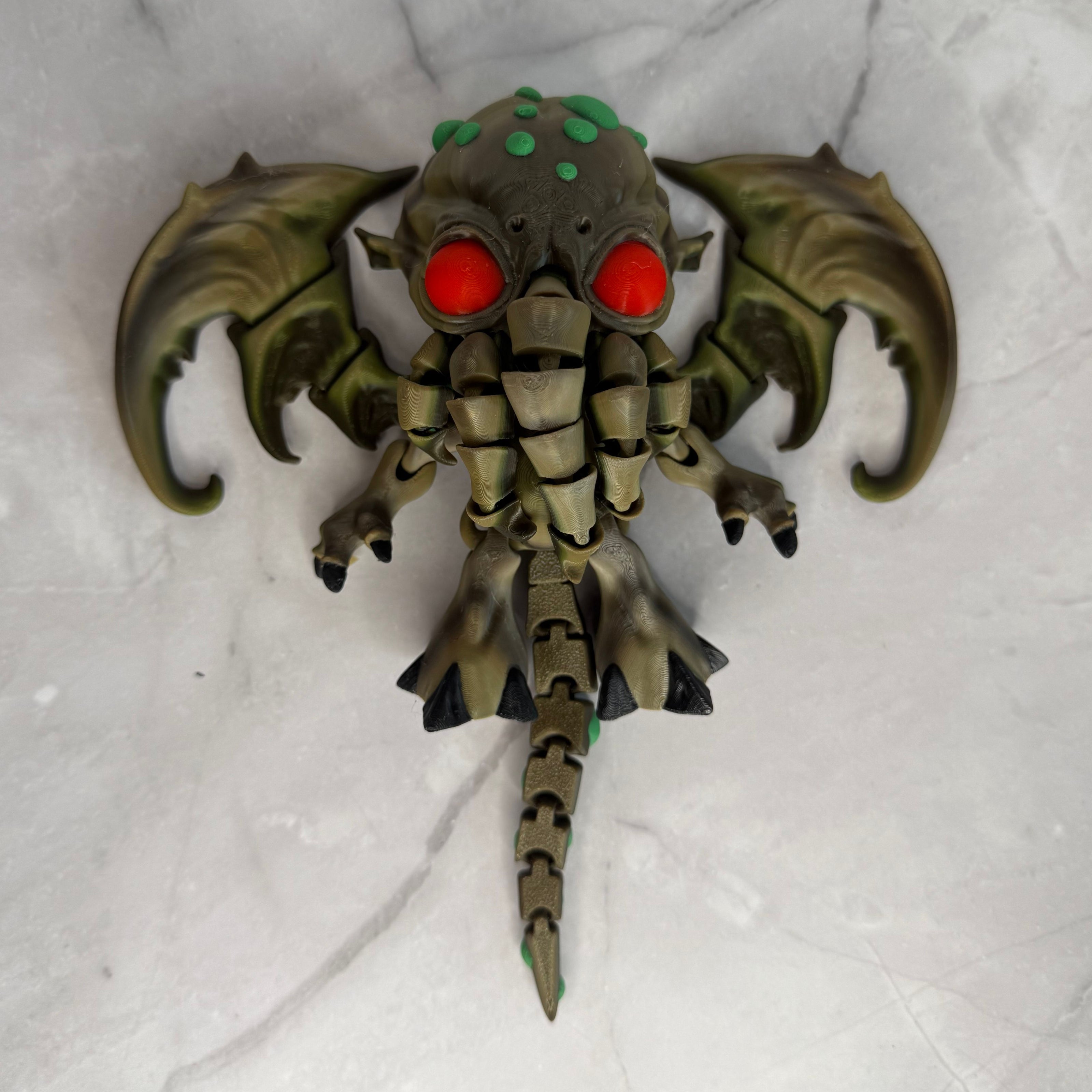 Toy figure of a creature with red eyes and green accents on a gray background