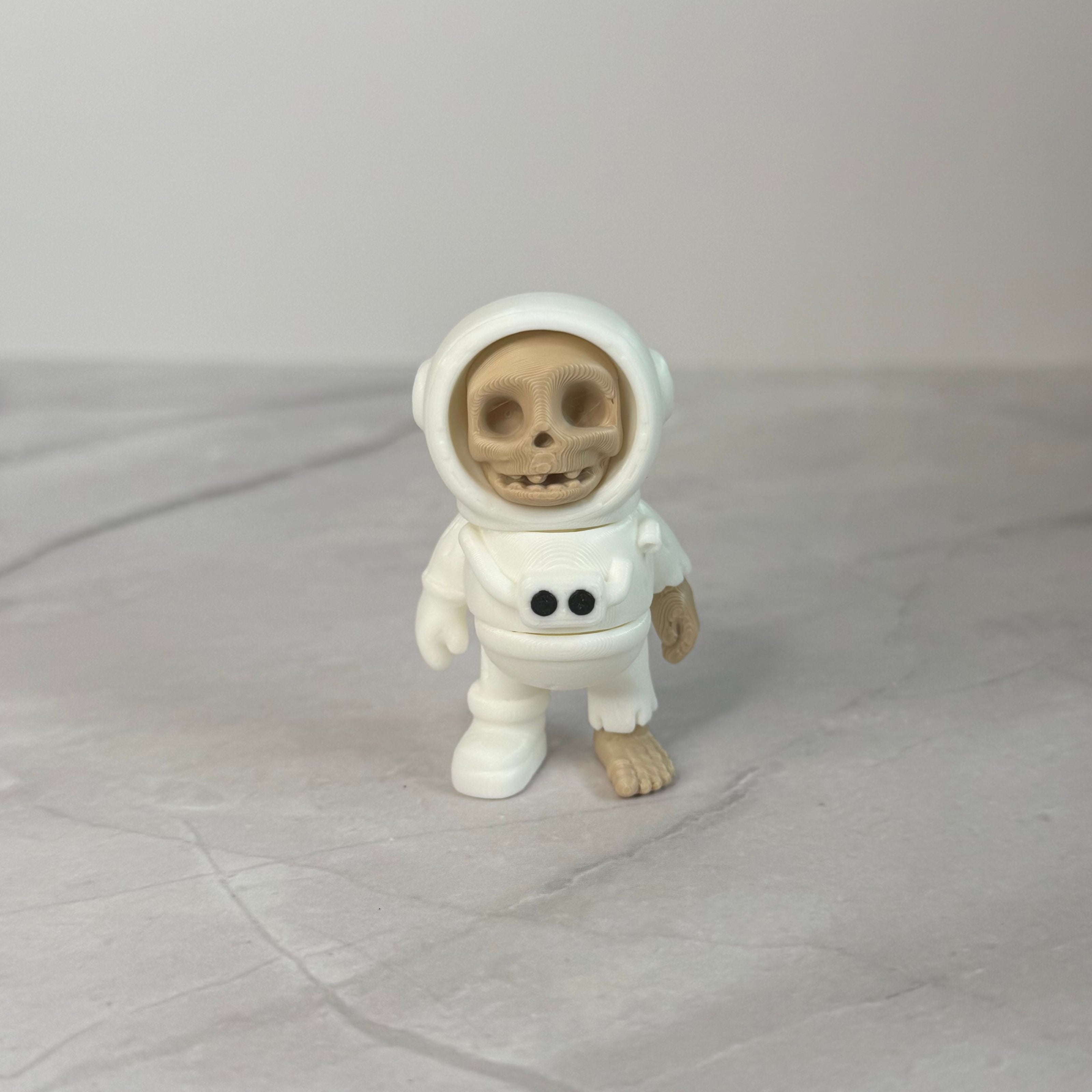 Small figure of a skeleton in an astronaut suit on a light gray background