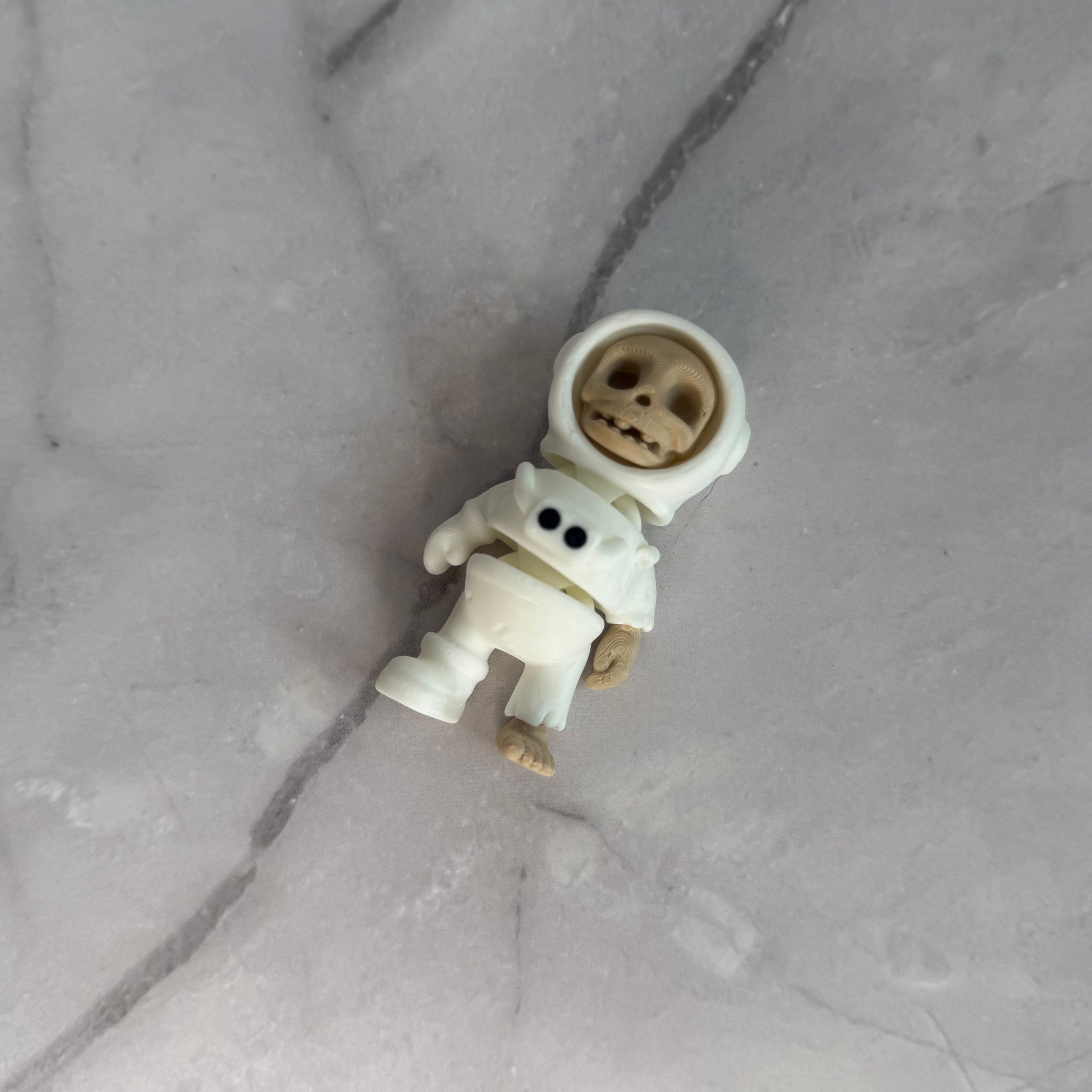 Small figure of a skeleton in an astronaut suit on a light gray background