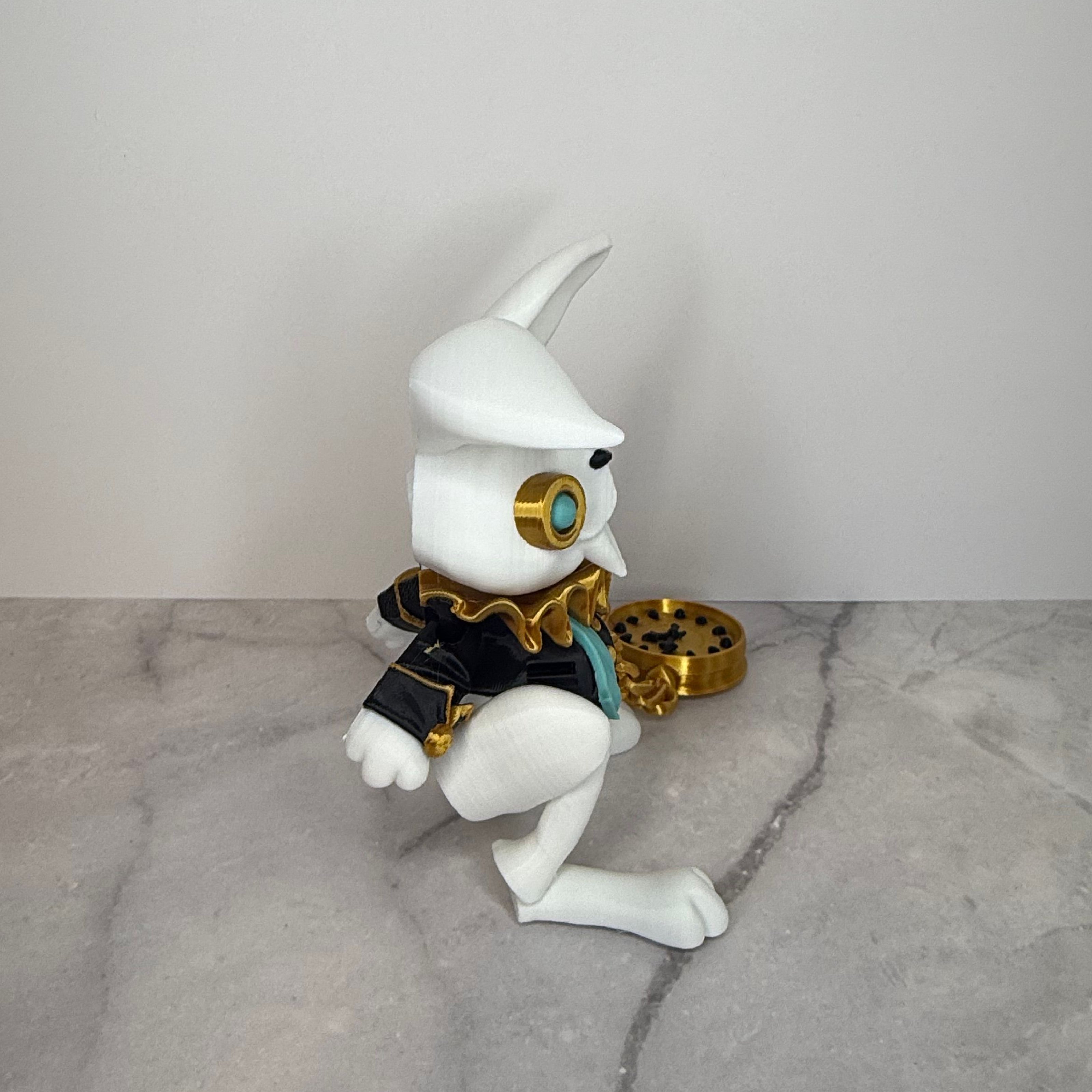 White rabbit figurine with gold and black accessories on a gray background