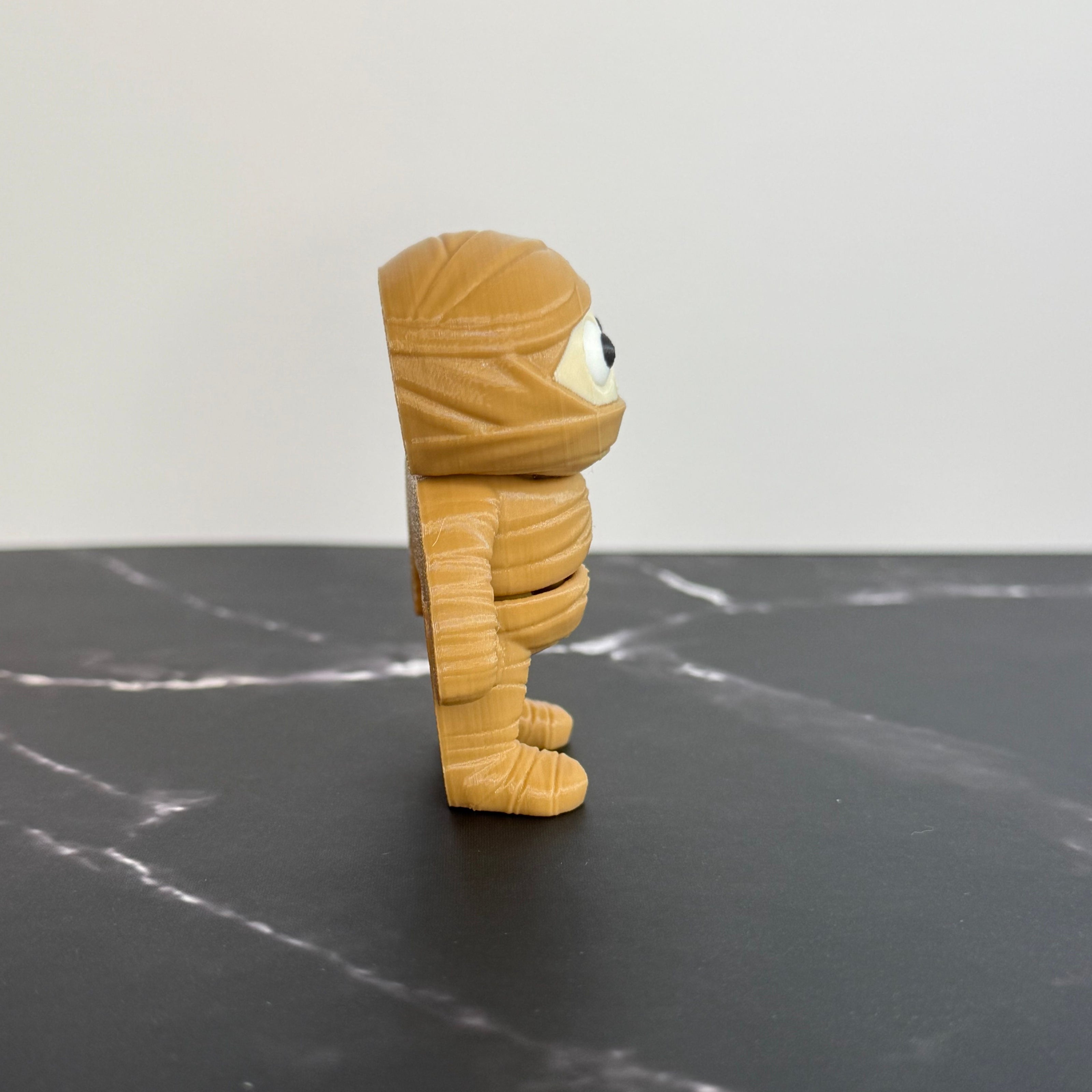 Toy figure of a mummy on a black surface with a white background