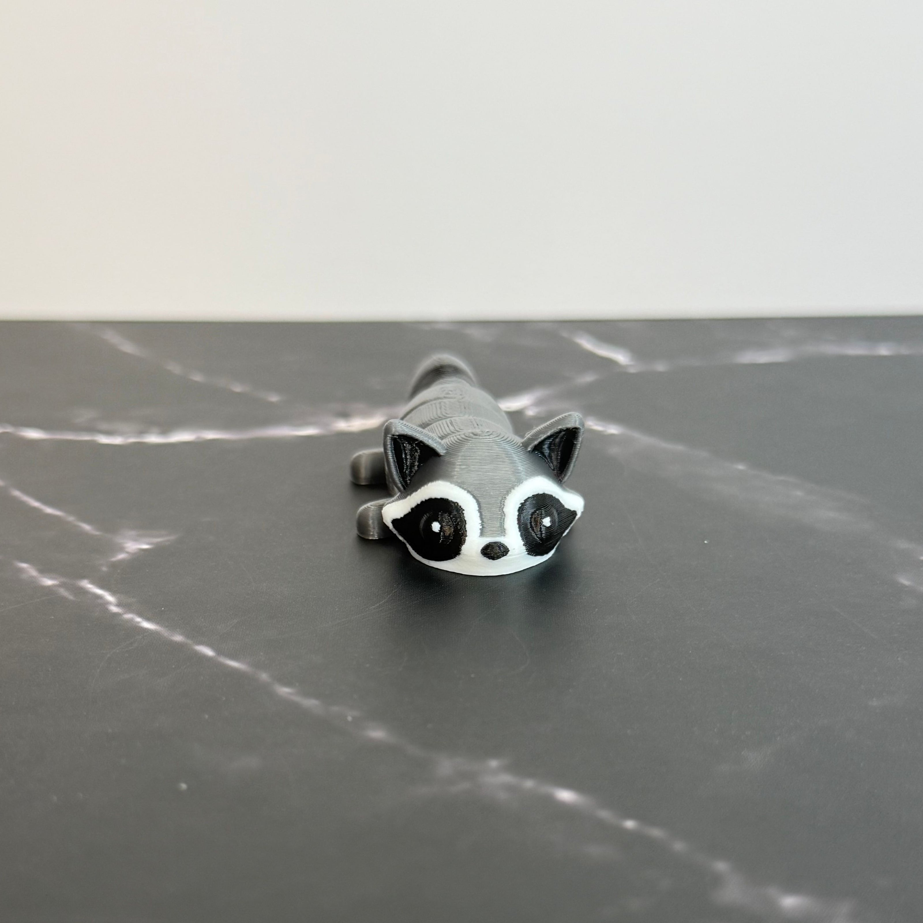 3D-printed raccoon toy on a black marble surface