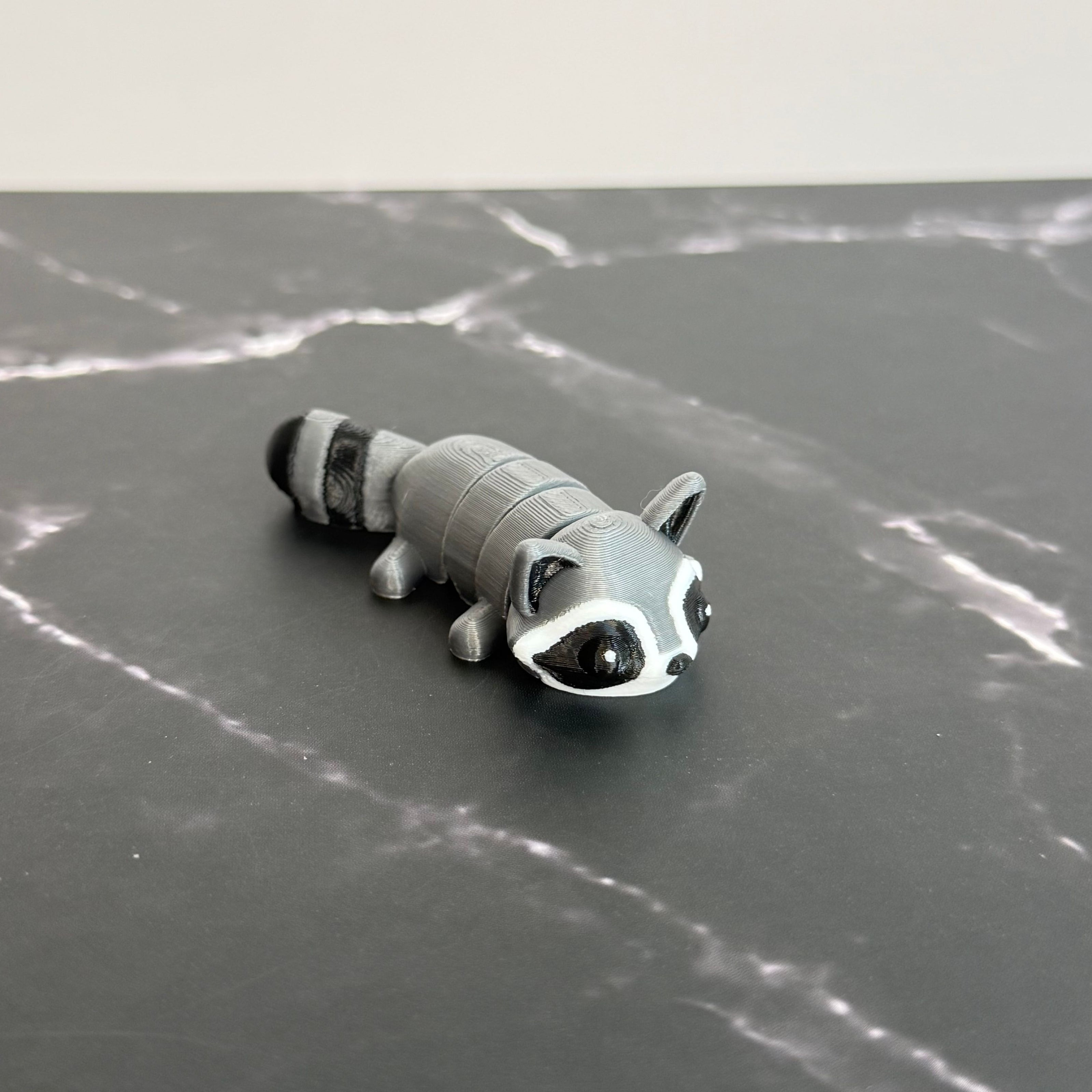 3D-printed raccoon toy on a black marble