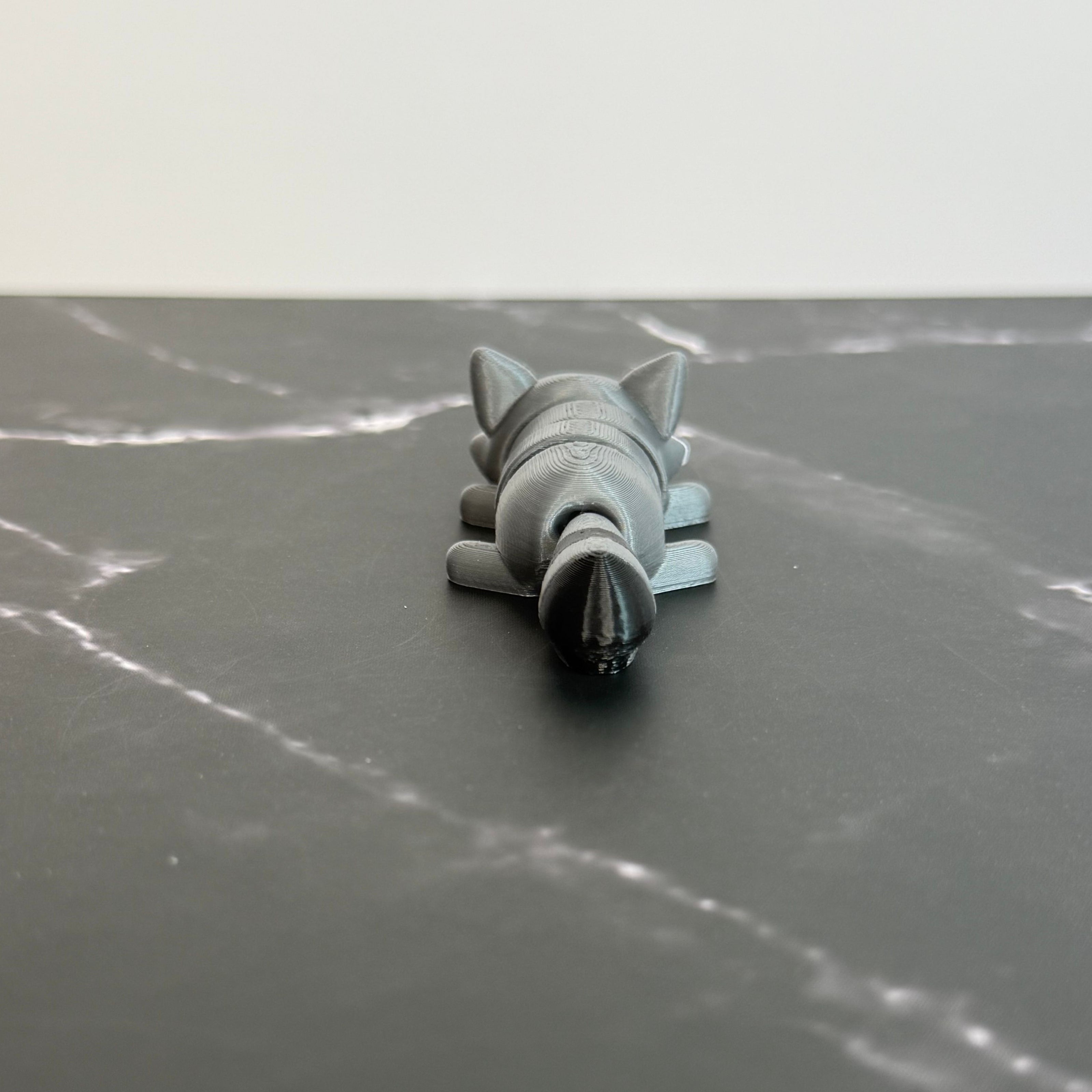 3D-printed raccoon toy on a black marble surface