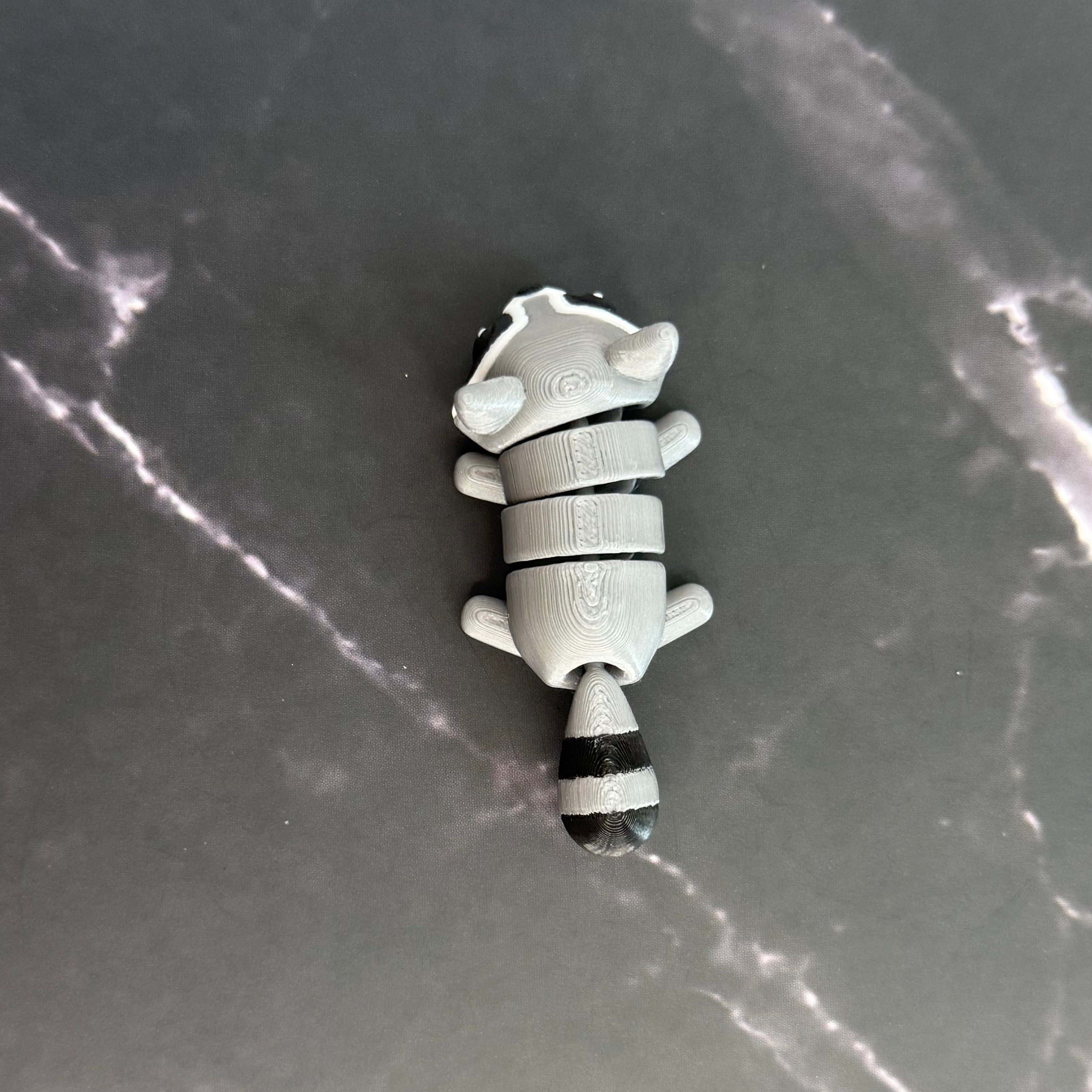 3D-printed raccoon toy on a black marble surface