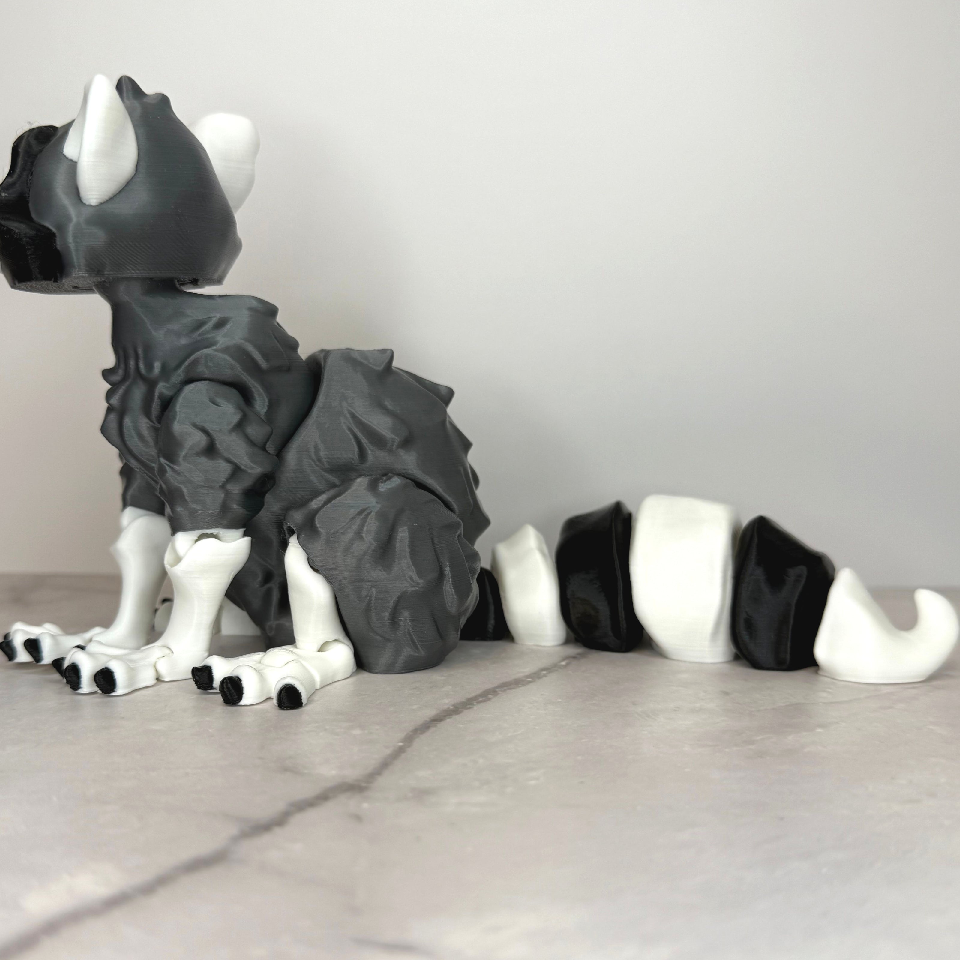Gray and white creature figurine on a light gray surface with a neutral background