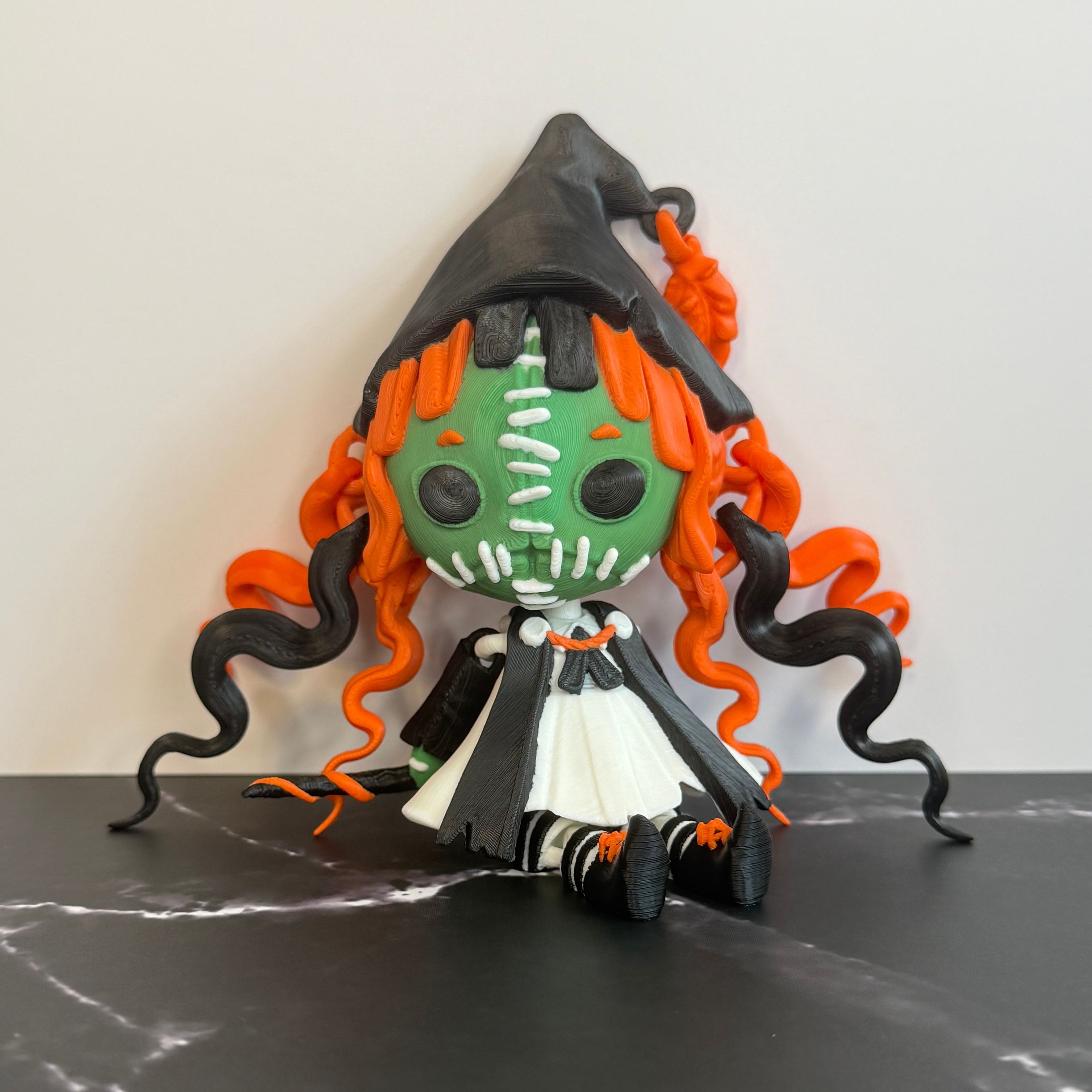 Toy figure with green face, orange and black hair on a dark surface