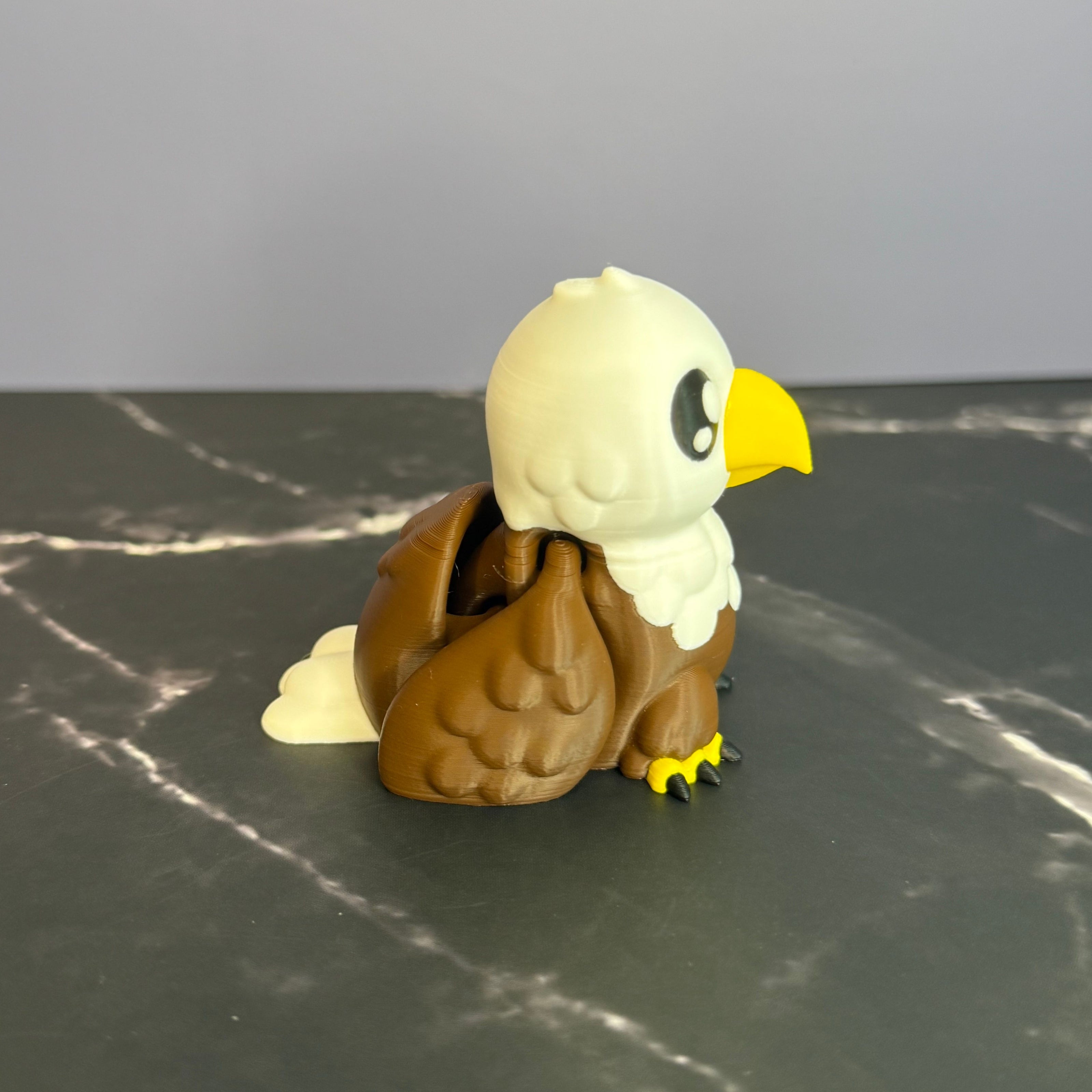Toy eagle figurine on a dark surface with a light blue and marble black background