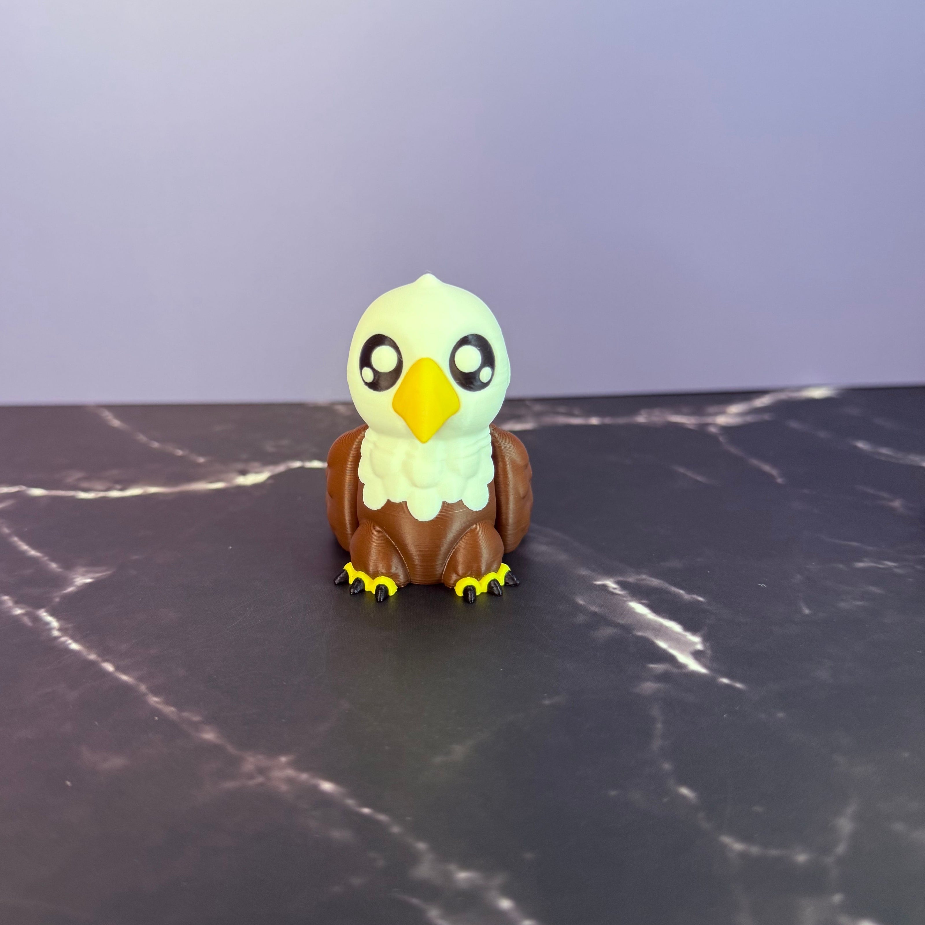 Toy eagle figurine on a dark surface with a light blue and marble black background