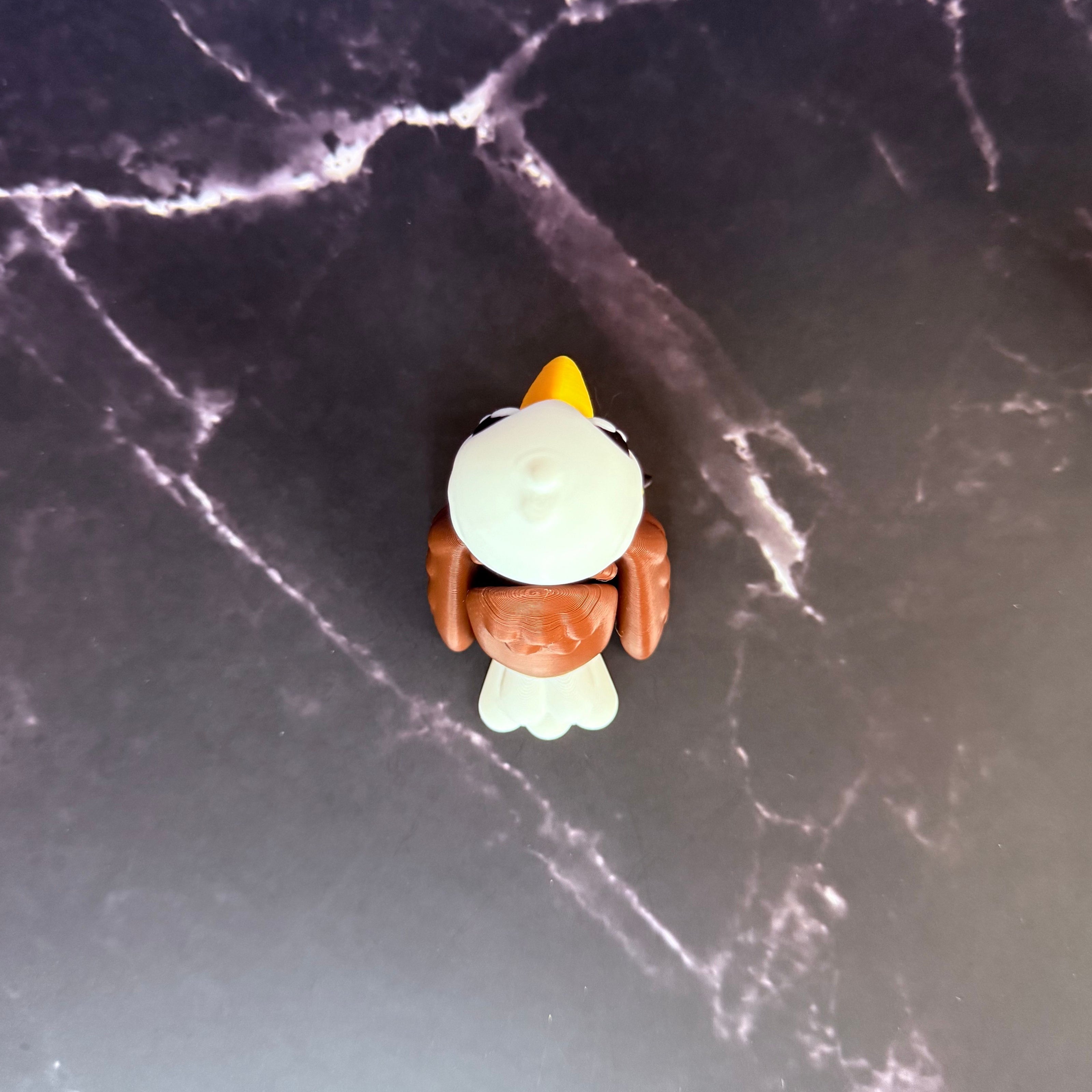 Toy eagle figurine on a dark surface with a light blue and marble black background
