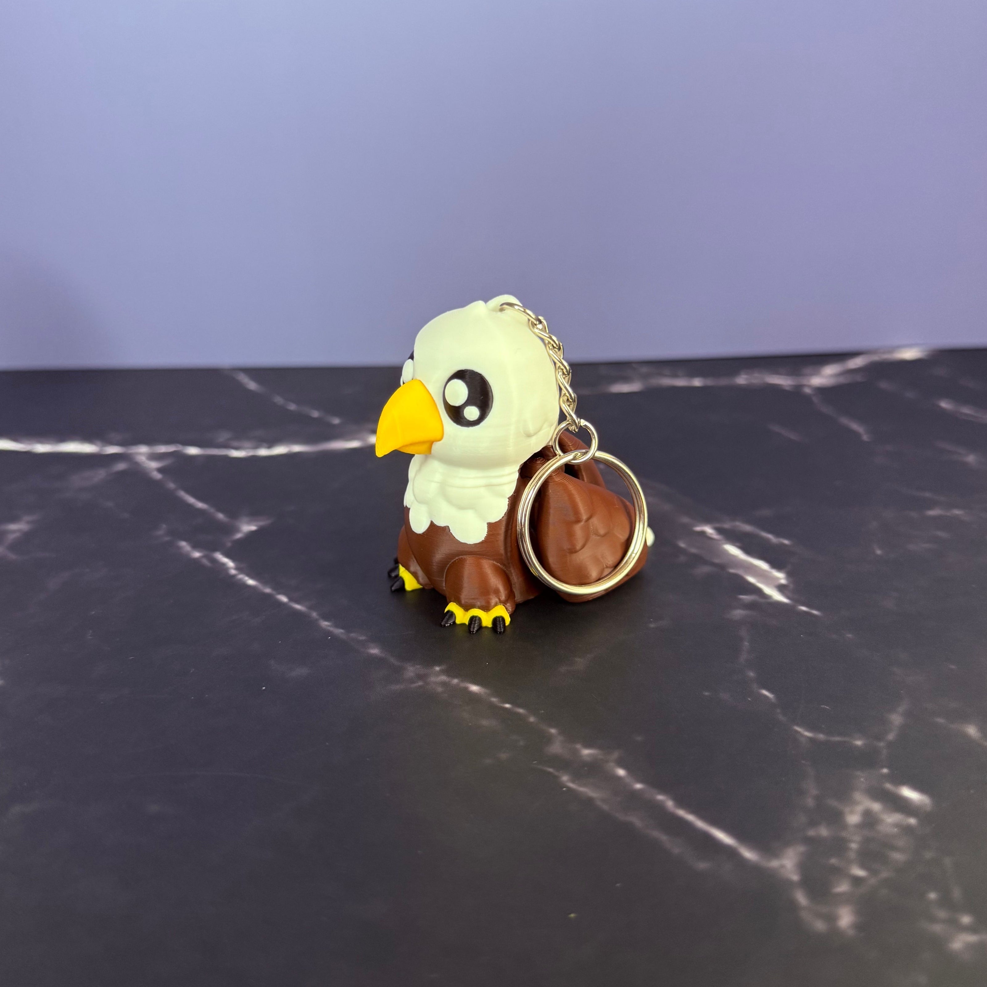 Eagle-shaped keychain on a dark marble surface with a blue background