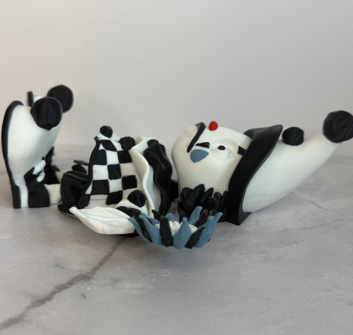 Black and white clown figurine with a hat and checkered outfit on a gray background