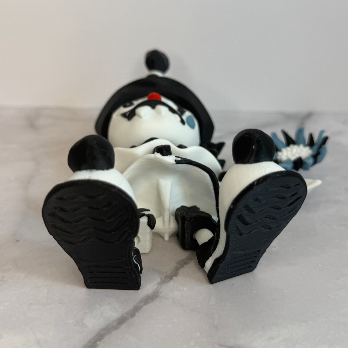 Black and white clown figurine with a hat and checkered outfit on a gray background