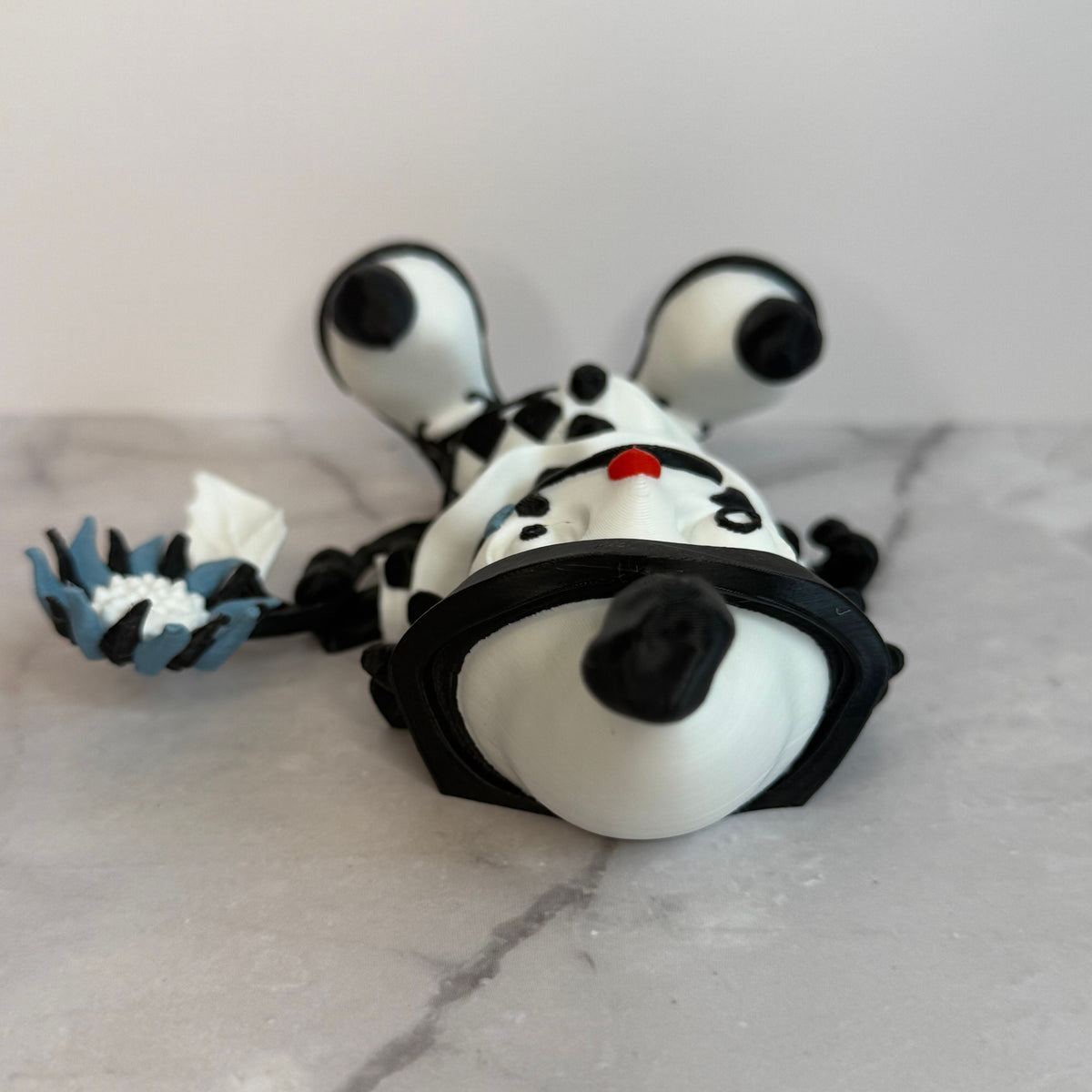 Black and white clown figurine with a hat and checkered outfit on a gray background