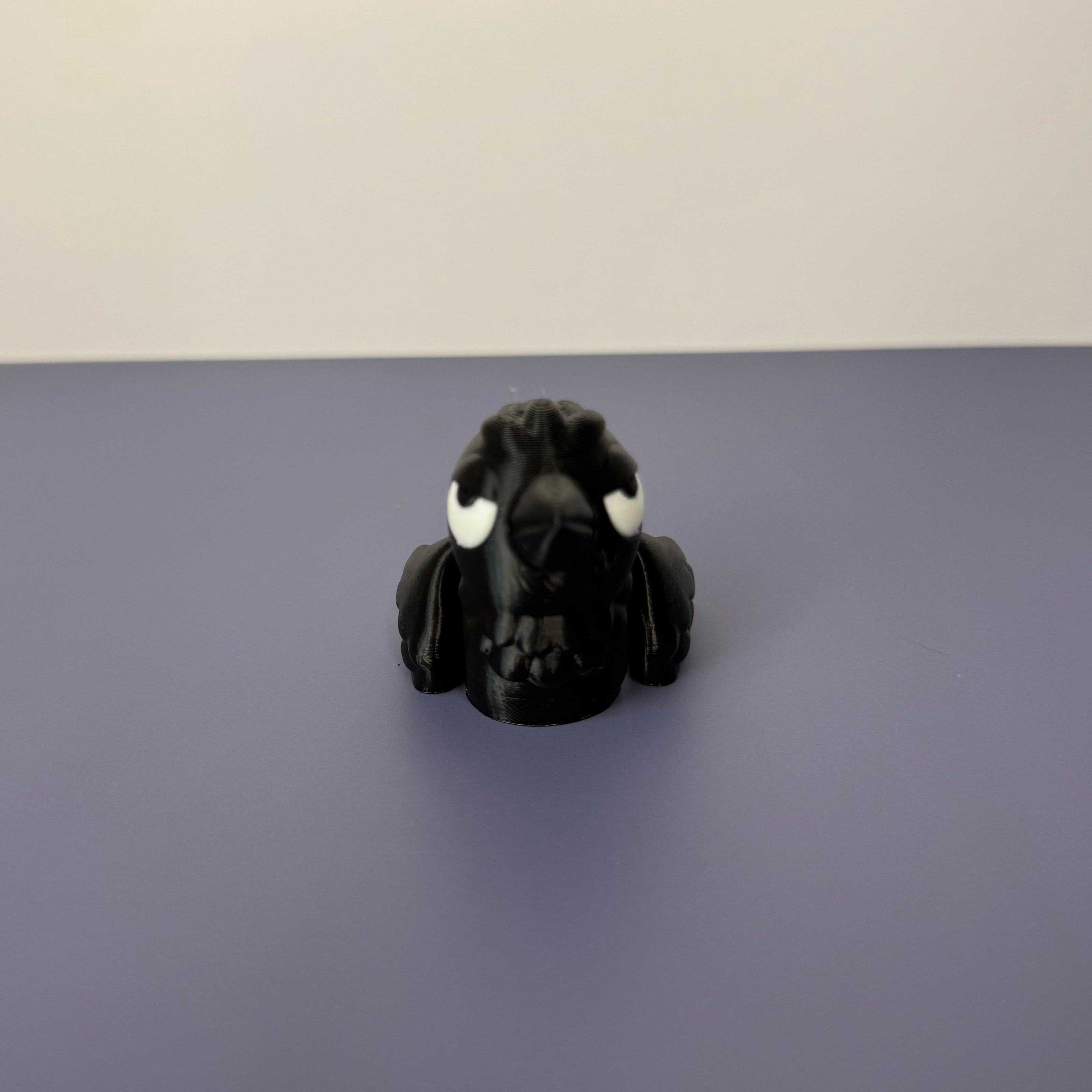 Front face of a black crow figure with white eyes on a blue background
