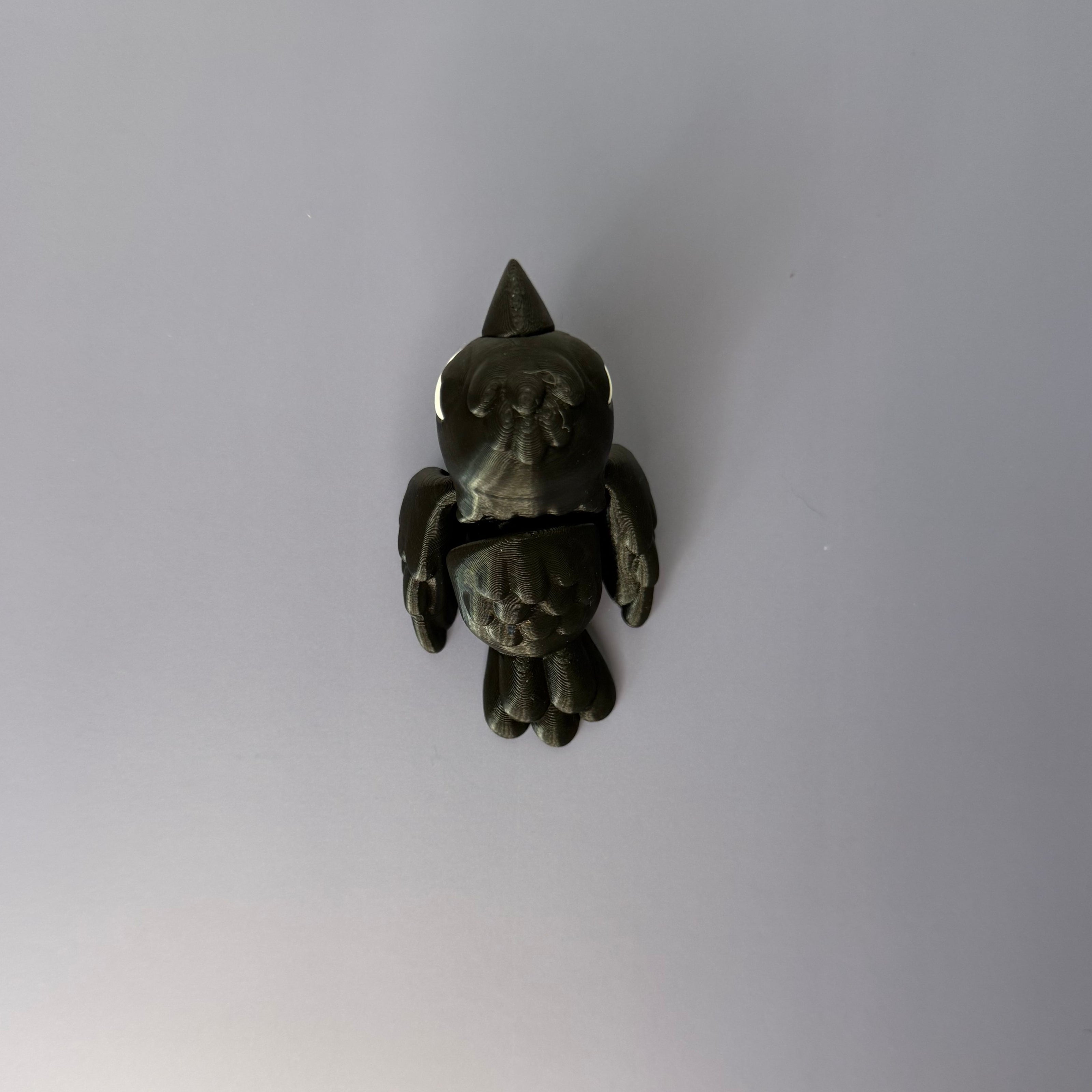 Top of black crow figure with white eyes on a blue background