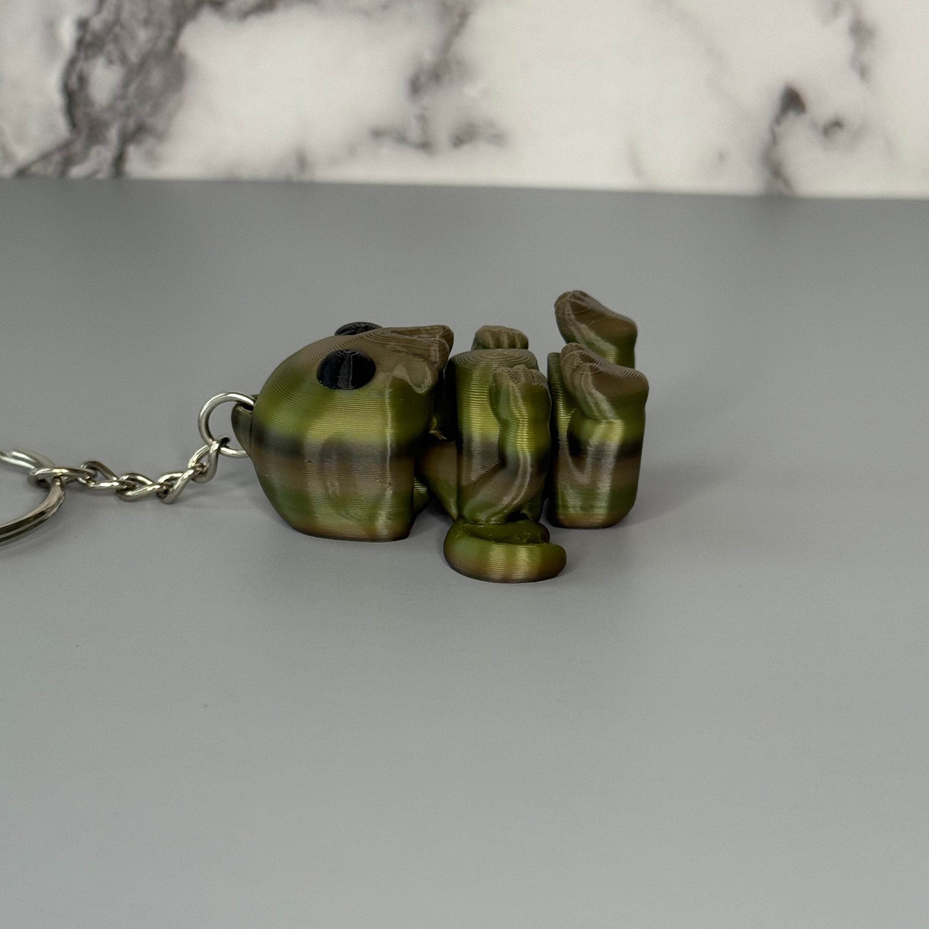 Side of Cthulhu-shaped keychain figure with wings and face-tentacles on a gray background