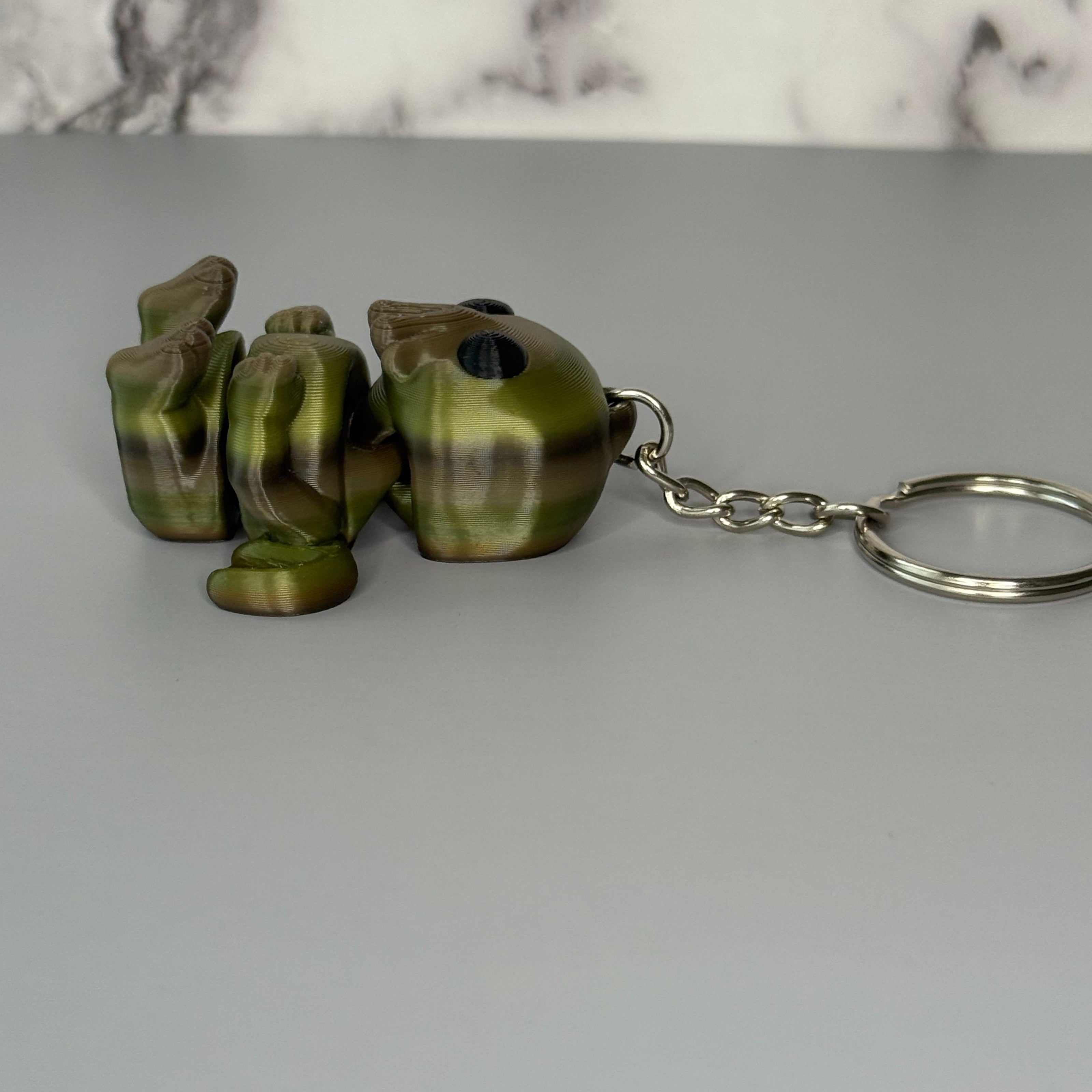 Side of a Cthulhu-shaped keychain figure with wings and face-tentacles on a gray background