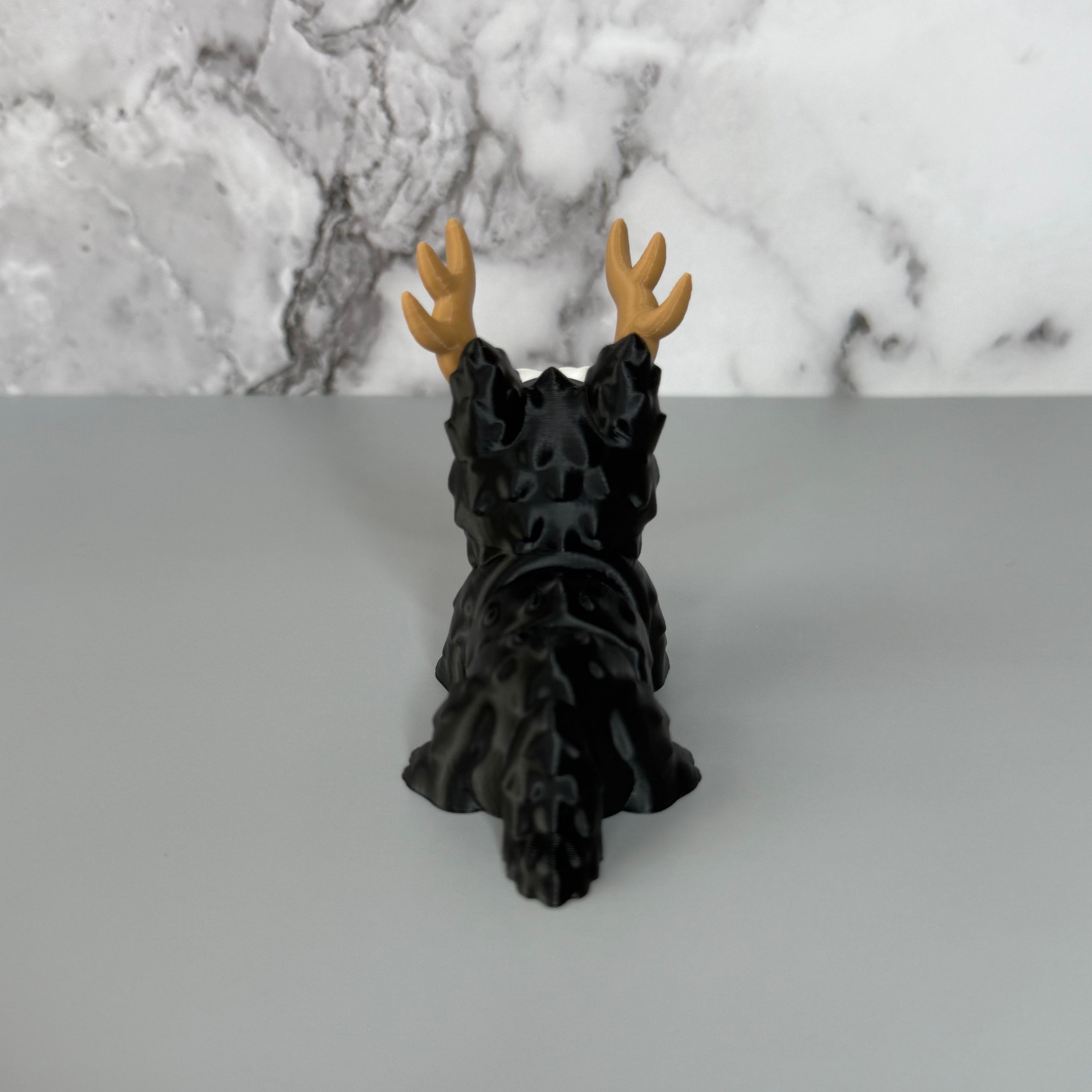 Back side of a four-legged black animal-shaped figure with antlers on a gray background