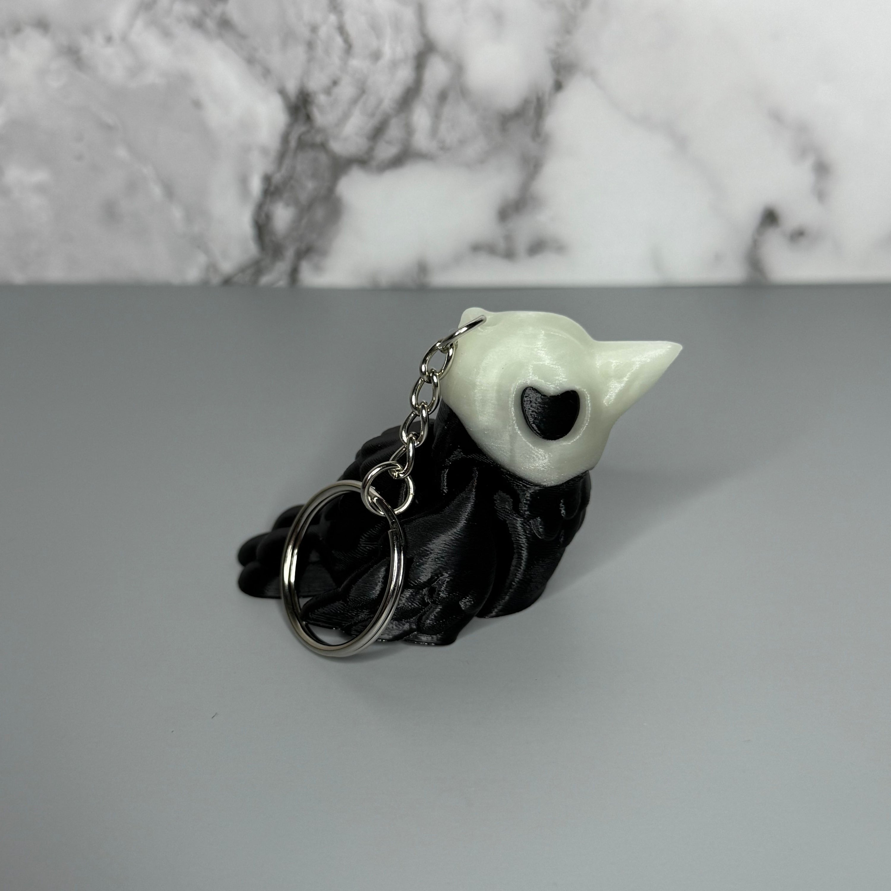 Left side of black and white crow-shaped keychain with crow-shaped skull head on light gray background