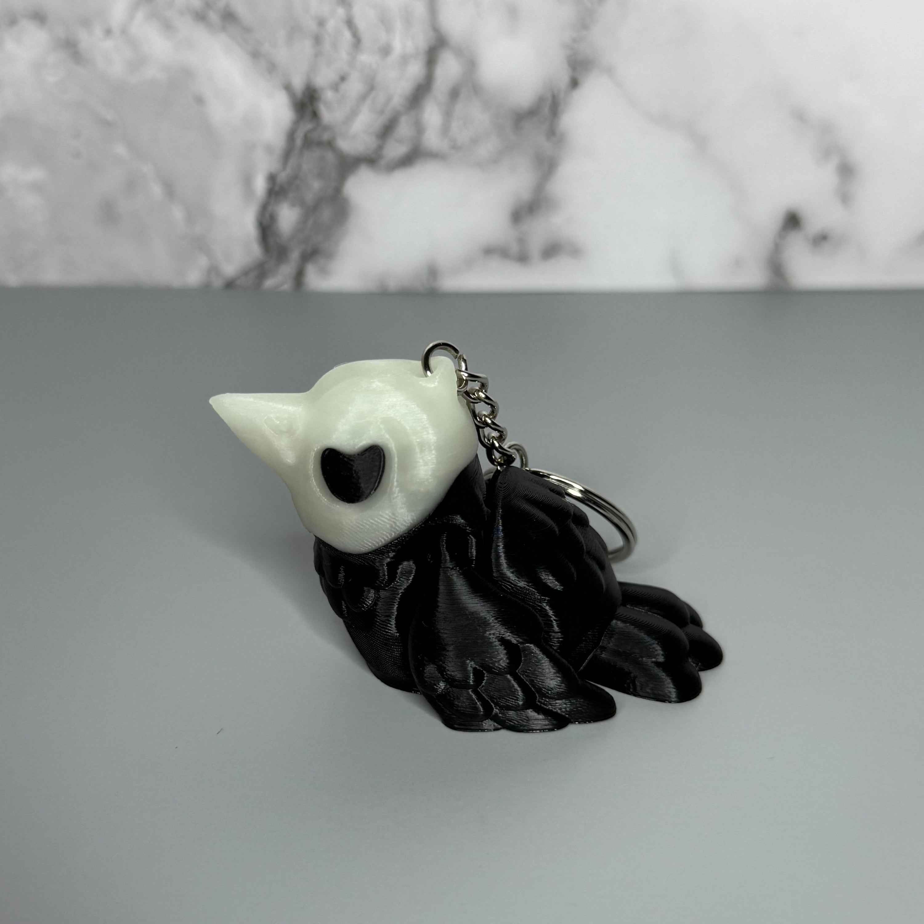 Right side of black and white crow-shaped keychain with crow-shaped skull head on light gray background