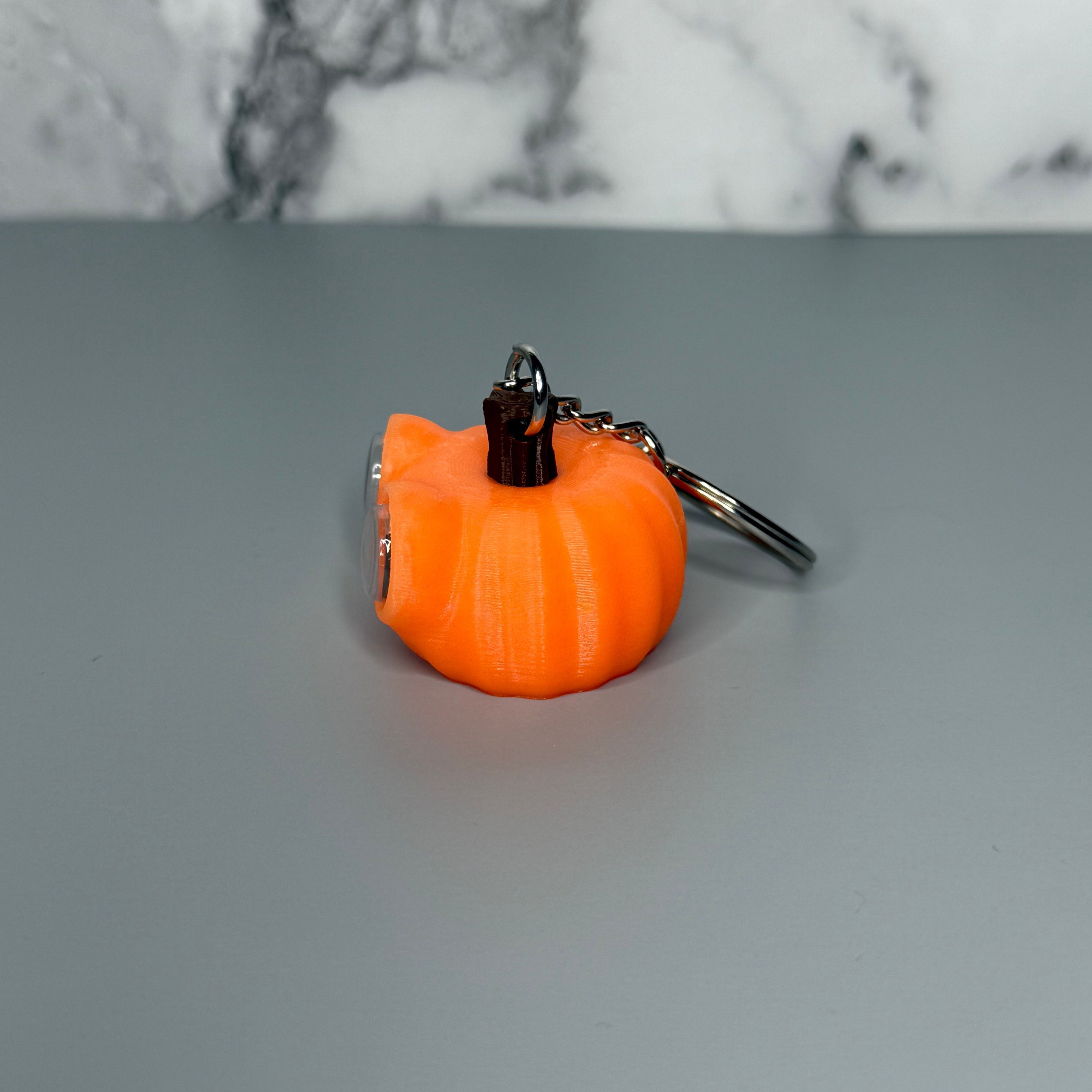 Right side of orange pumpkin-shaped keychain with googly eyes on a gray background