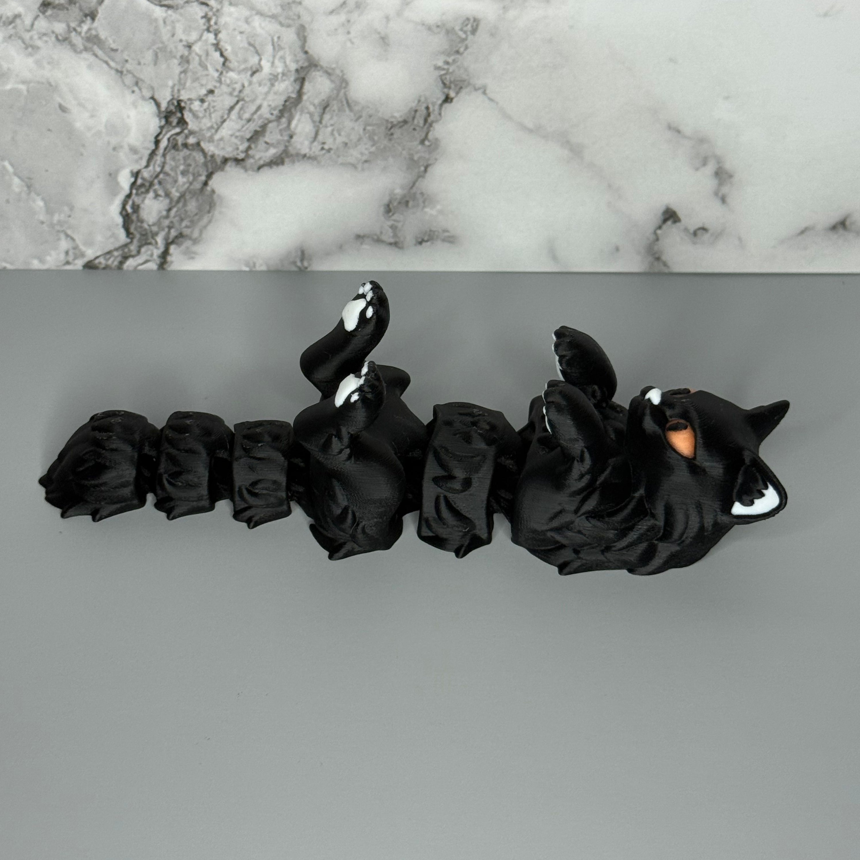 Black cat-shaped figure on a gray and marble surface