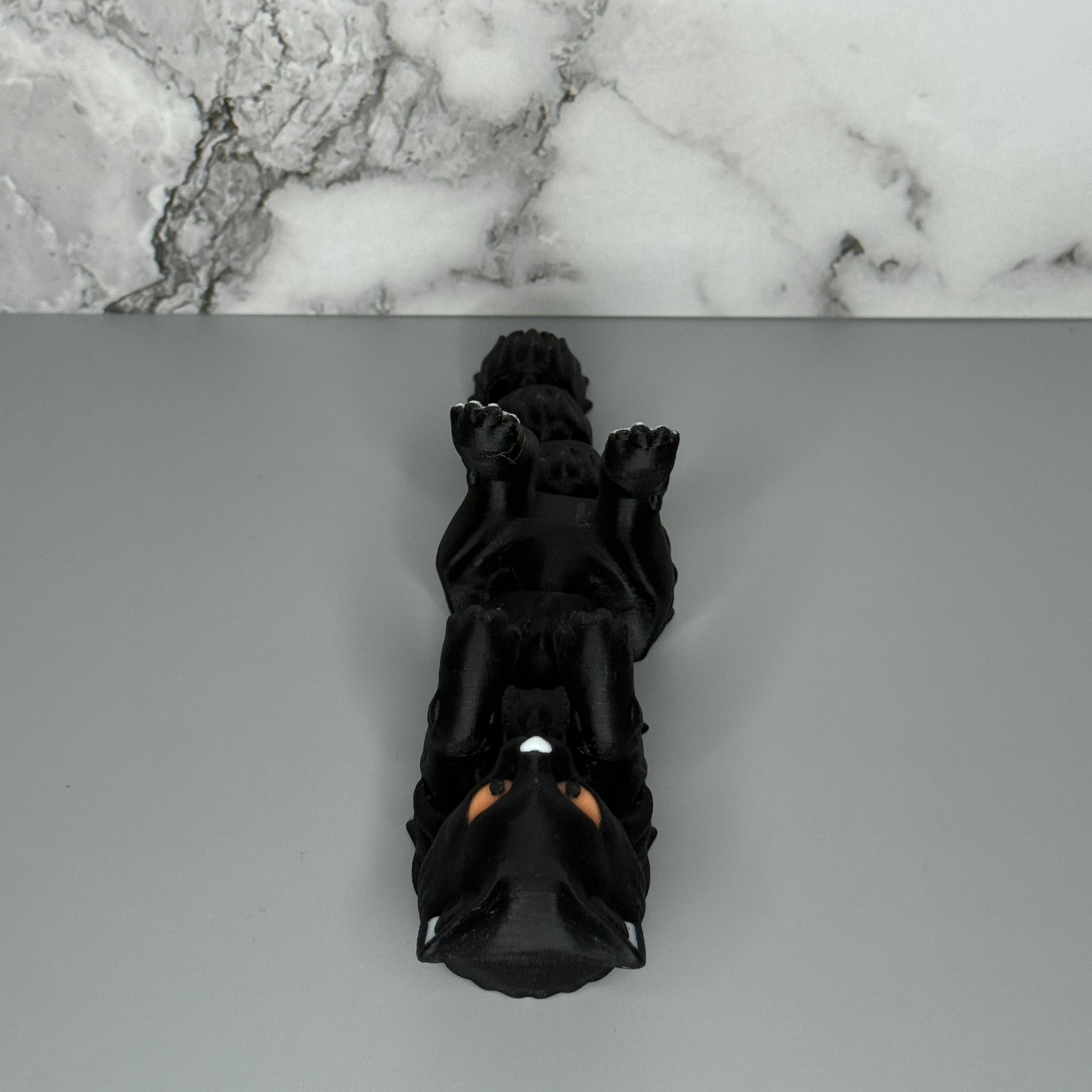 Black cat-shaped figure on a gray and marble surface