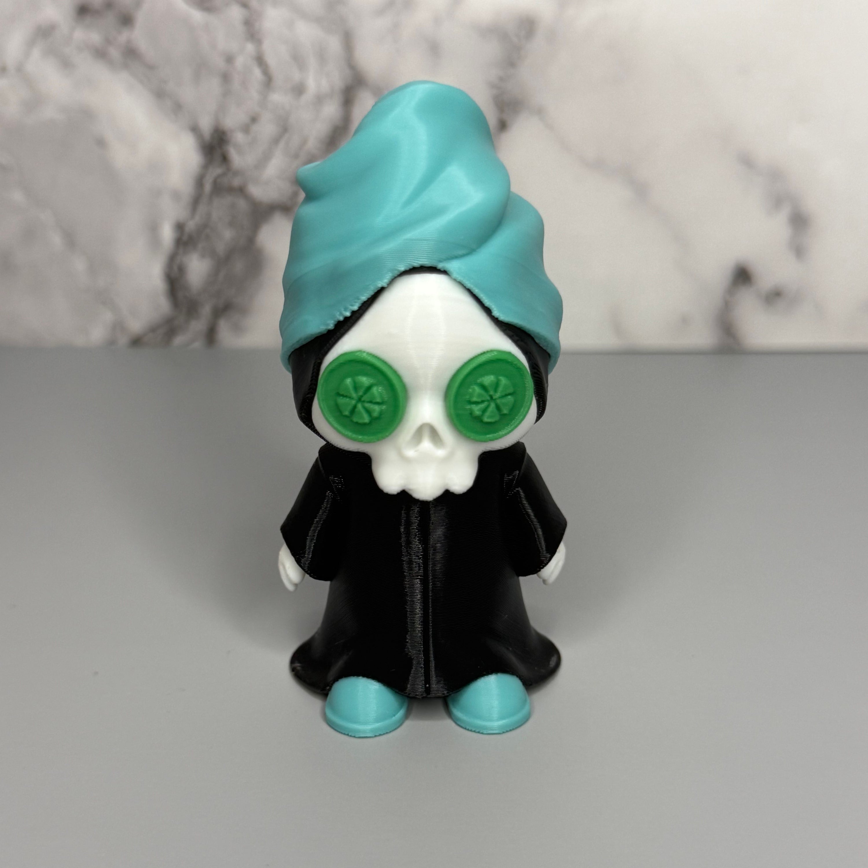 Grim reaper figure with teal head towel and shoes, black cloak, and green discs on eyes on a gray marble background