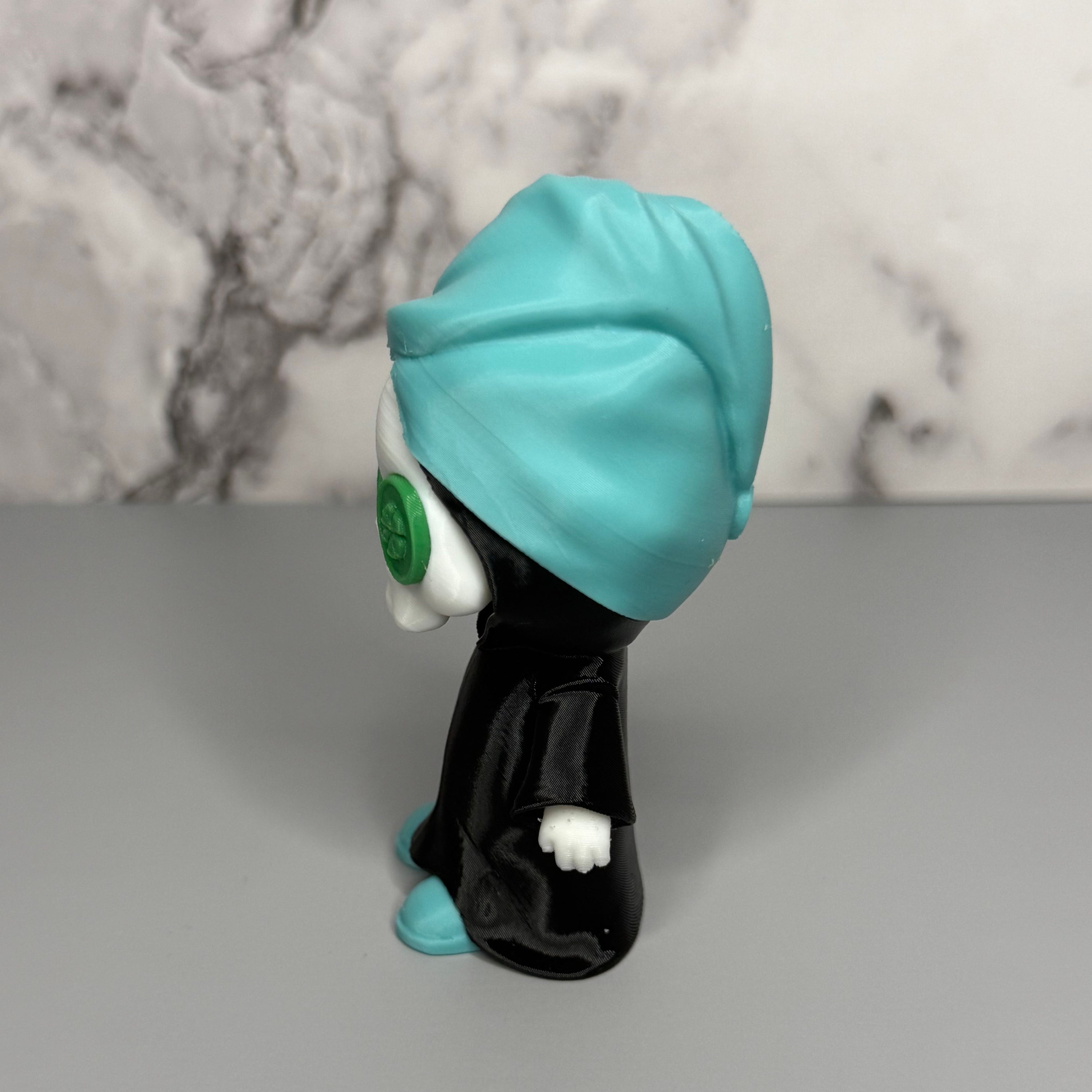 Right side of grim reaper figure with teal head towel and shoes, black cloak, and green discs on eyes on a gray marble background